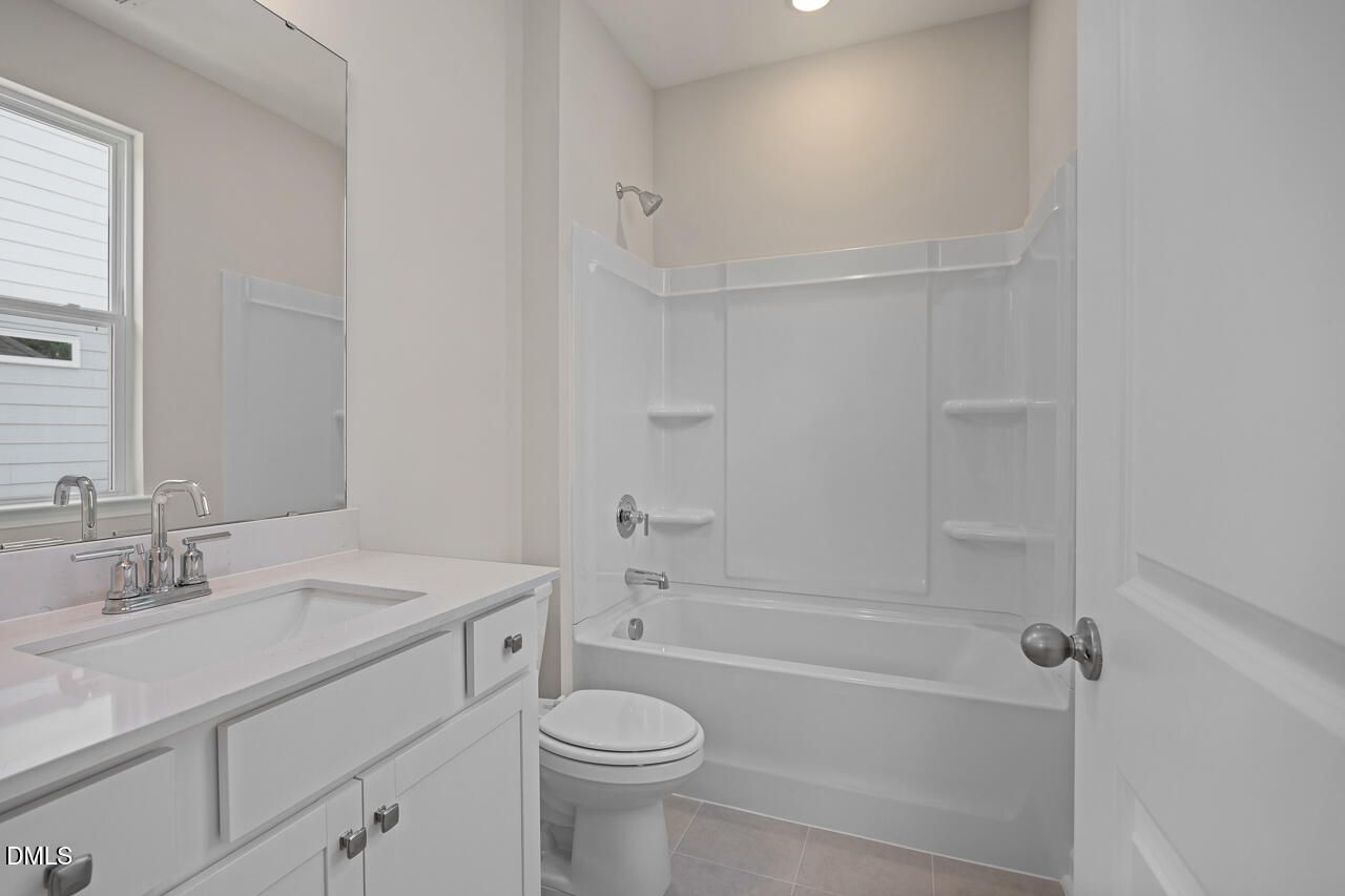 Modern bathroom with white vanity, quartz countertop, and tub-shower combo in Ashport G floor plan, Wake Forest, NC.