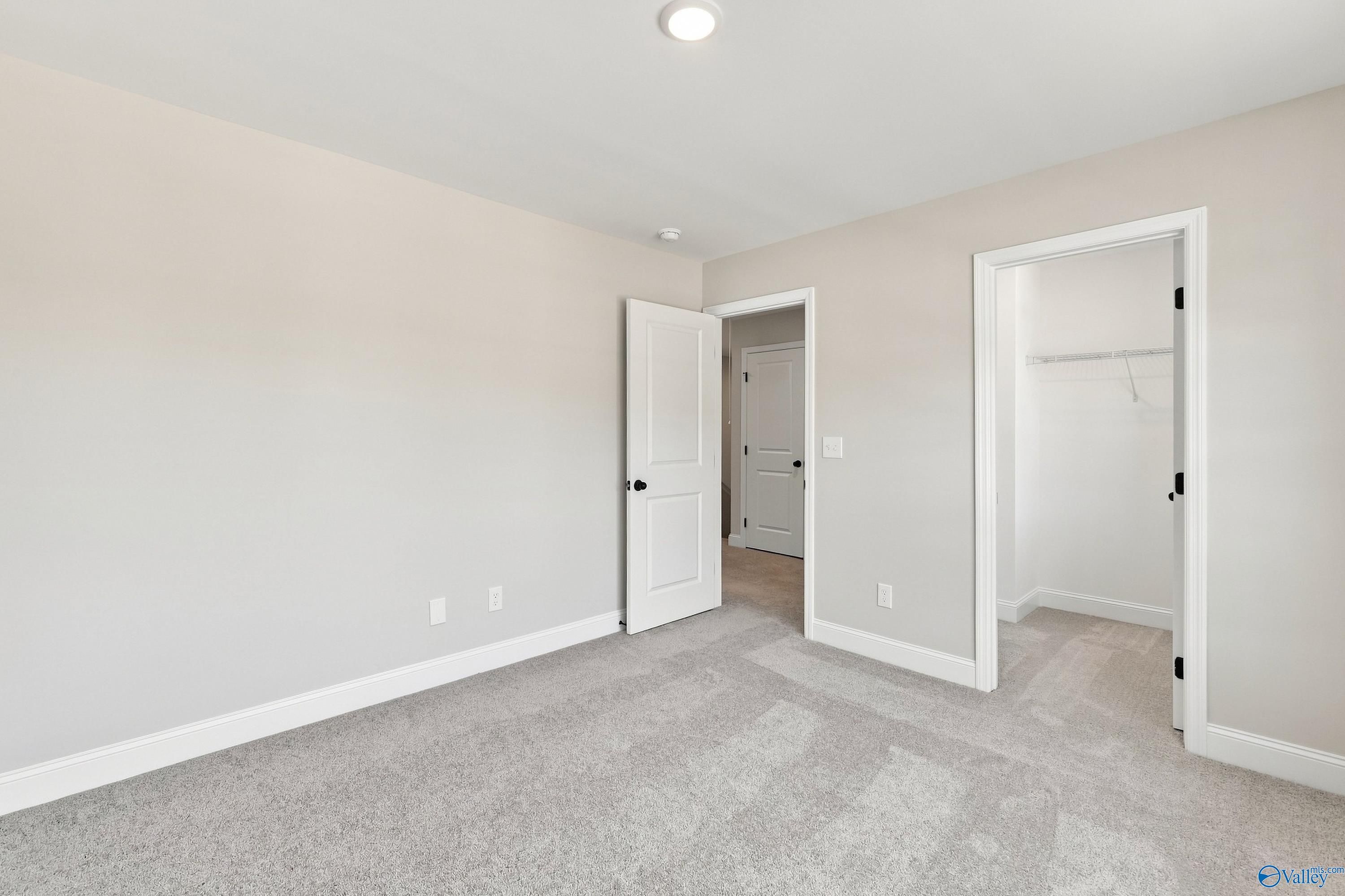 Bright bedroom with gray carpet, white doors, and walk-in closet in Davidson Homes' Chelsea B plan, Creek Grove, New Market, AL