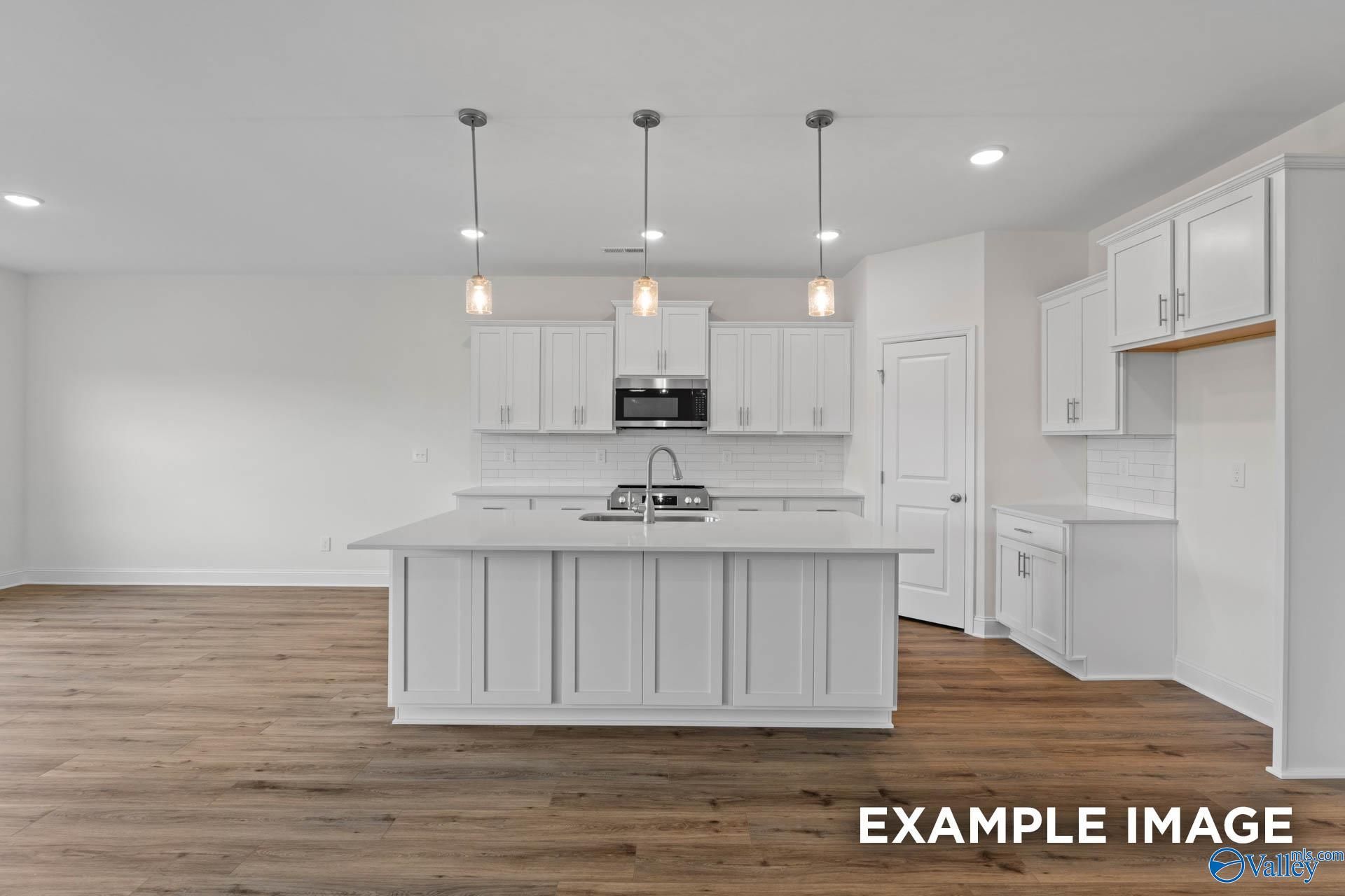 Modern gourmet kitchen with a large center island and white cabinetry in The Rockford B floor plan at Kendall Downs, Toney.