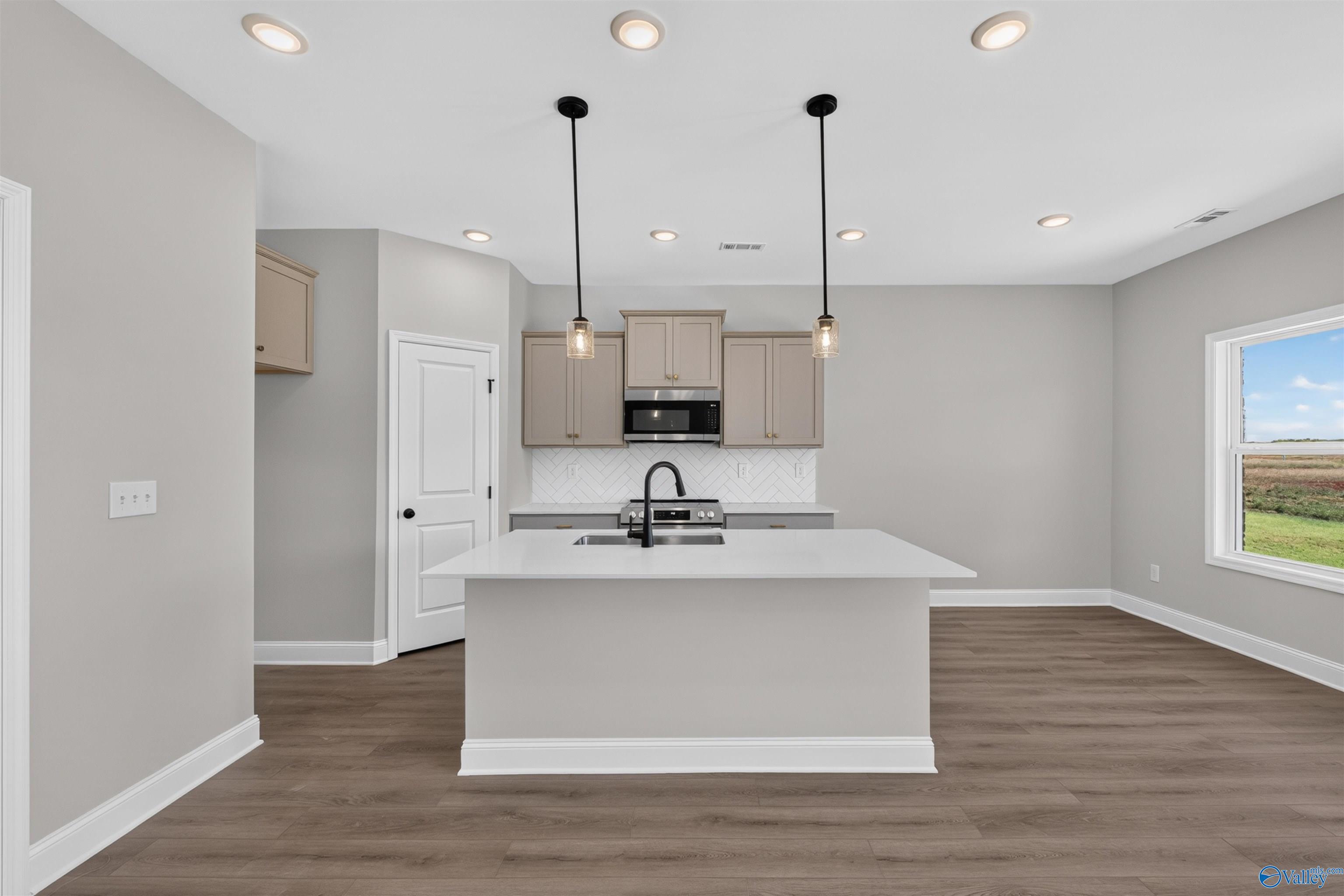 Bright open-concept kitchen with island sink, herringbone backsplash, and pendant lights in Davidson Homes The Butler plan, Hazel Green, AL
