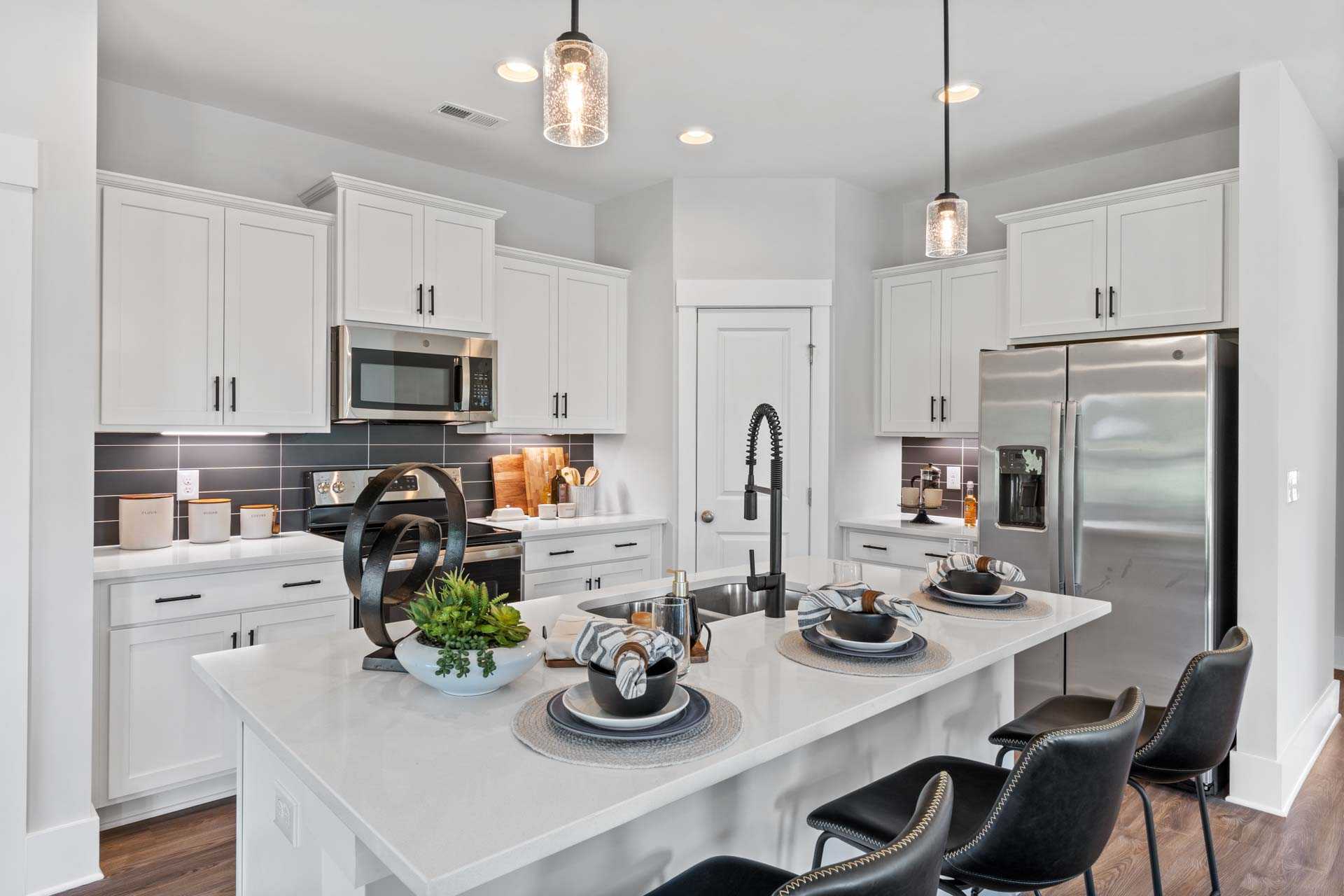 Modern white kitchen with quartz island, stainless appliances and pendant lights at Blue Spring in Huntsville AL by Davidson Homes