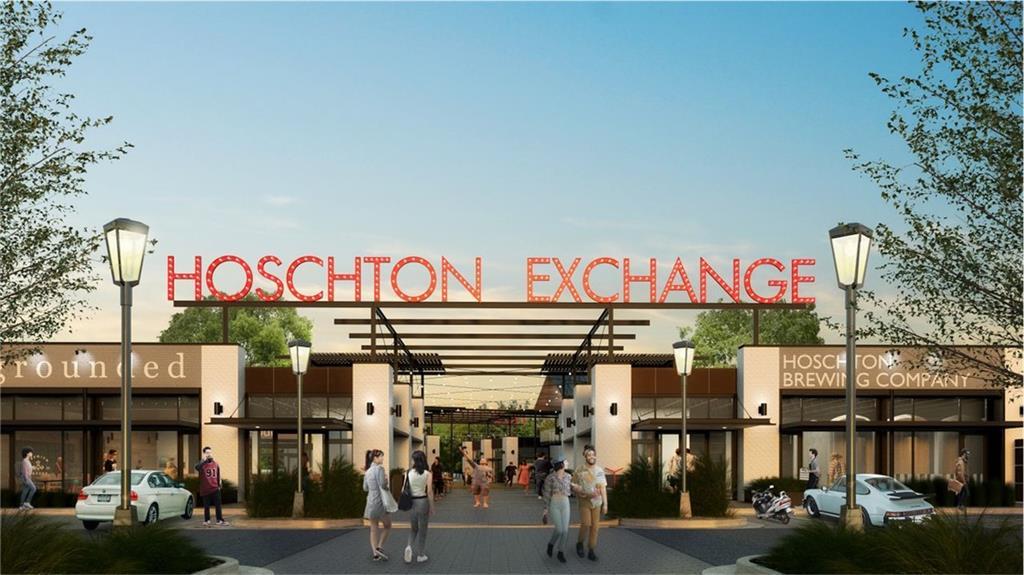 Inviting Hoschton Exchange entrance with red archway signage, modern retail storefronts, pedestrians, and parked cars in Hoschton, Georgia