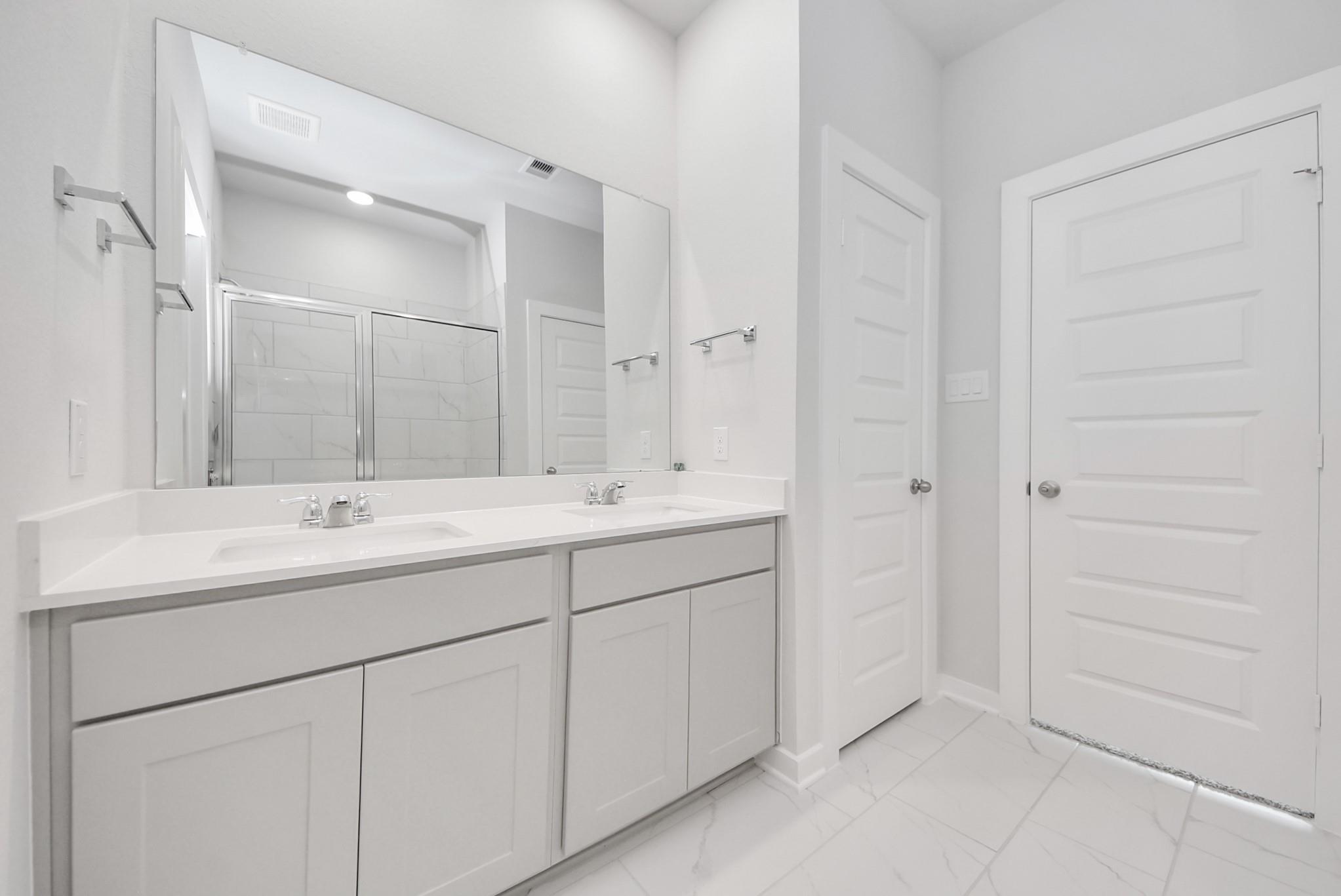Modern dual-sink bathroom vanity with white countertops in The Blanco F floor plan at Spring Branch Crossing in Conroe.