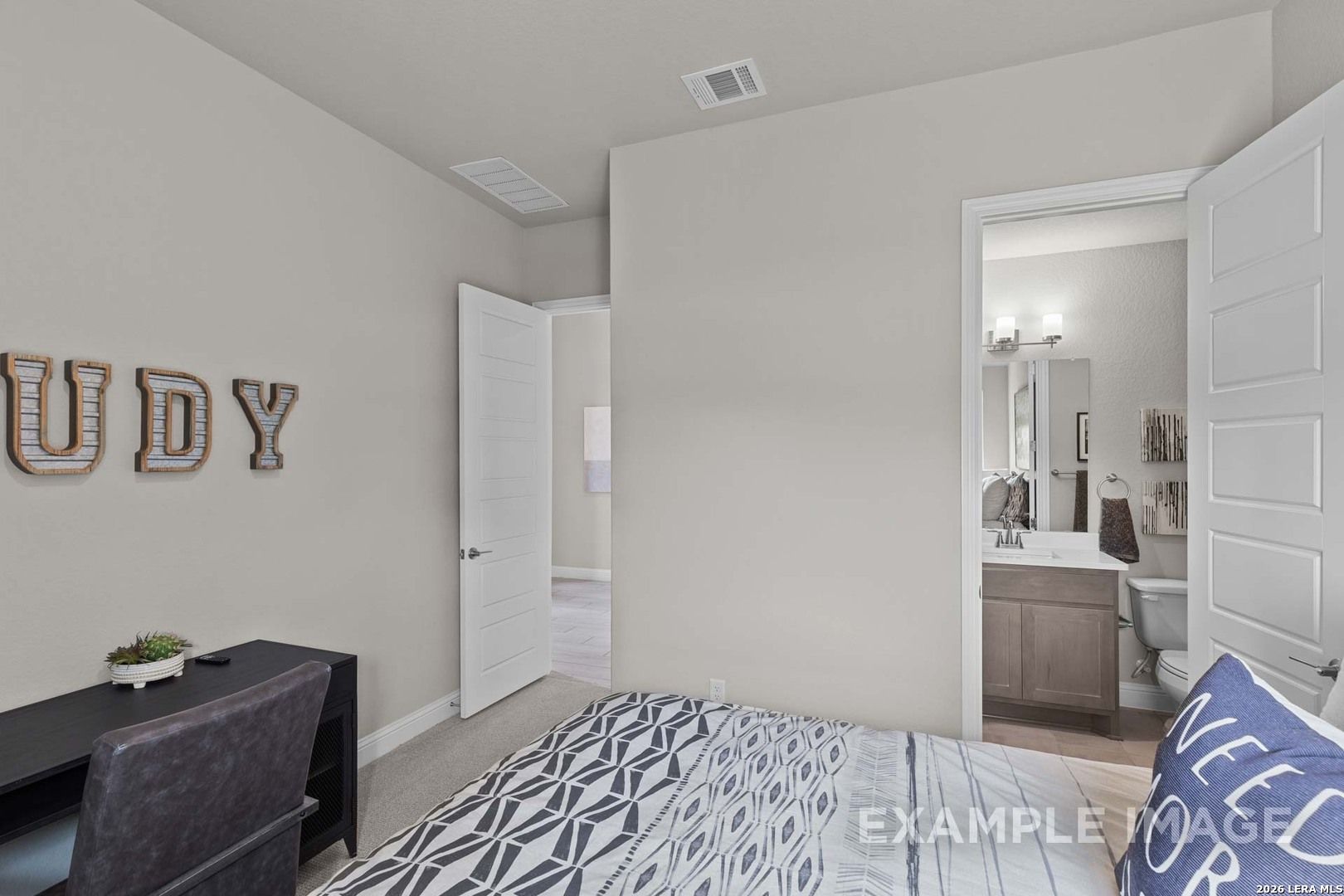 Spacious bedroom with attached bathroom and study area in The Garner C plan by Davidson Homes in Potranco Oaks, TX.