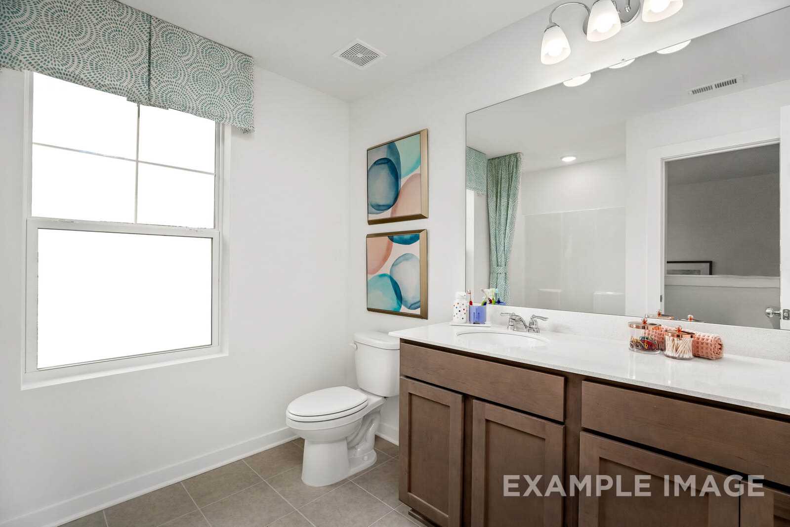 Spacious master bathroom in The Gordon B home featuring double vanity, large mirror, teal shower curtain, and abstract wall art