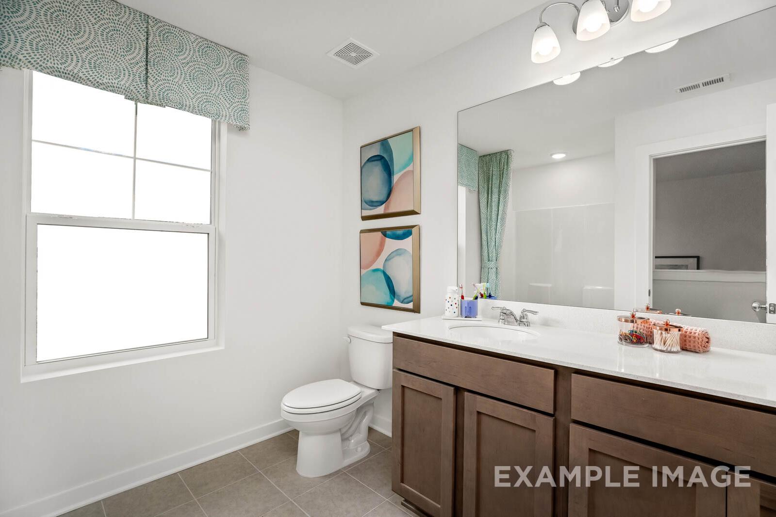 Modern master bathroom in The Gordon C home featuring double vanity, large mirror, abstract wall art, and teal window accents