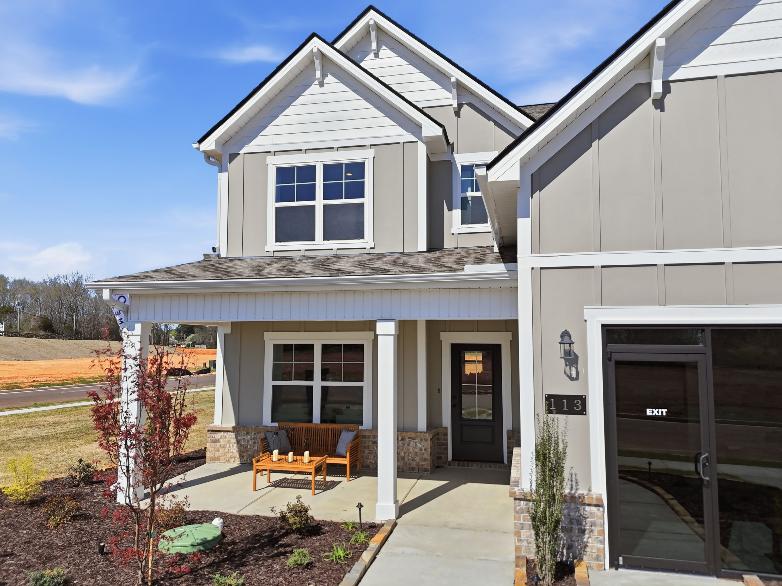 Two-story modern home exterior at Berry Cove in New Market Alabama with covered front porch, wooden bench, and landscaped yard