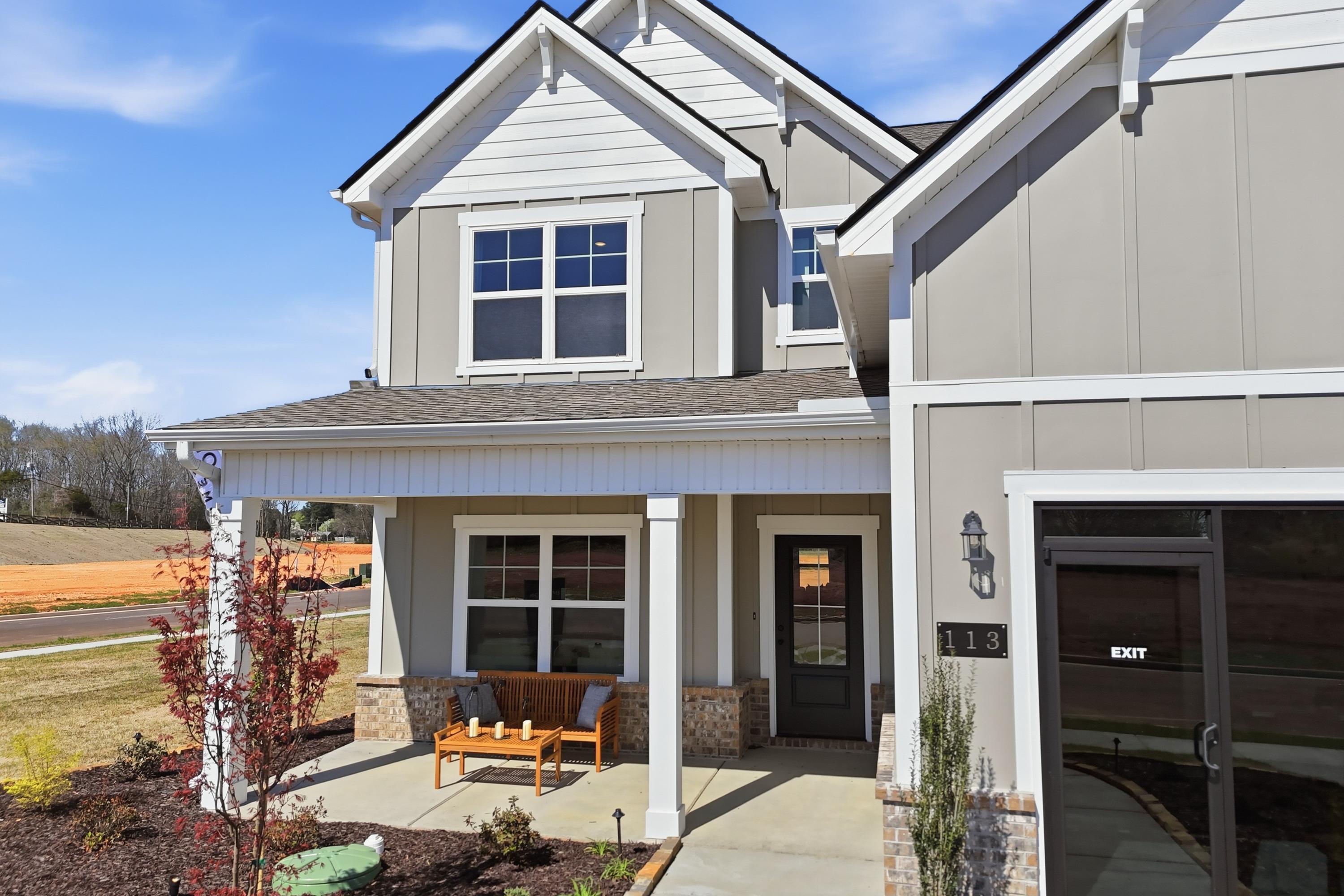 Two-story modern home exterior at Berry Cove in New Market Alabama with covered front porch, wooden bench, and landscaped yard