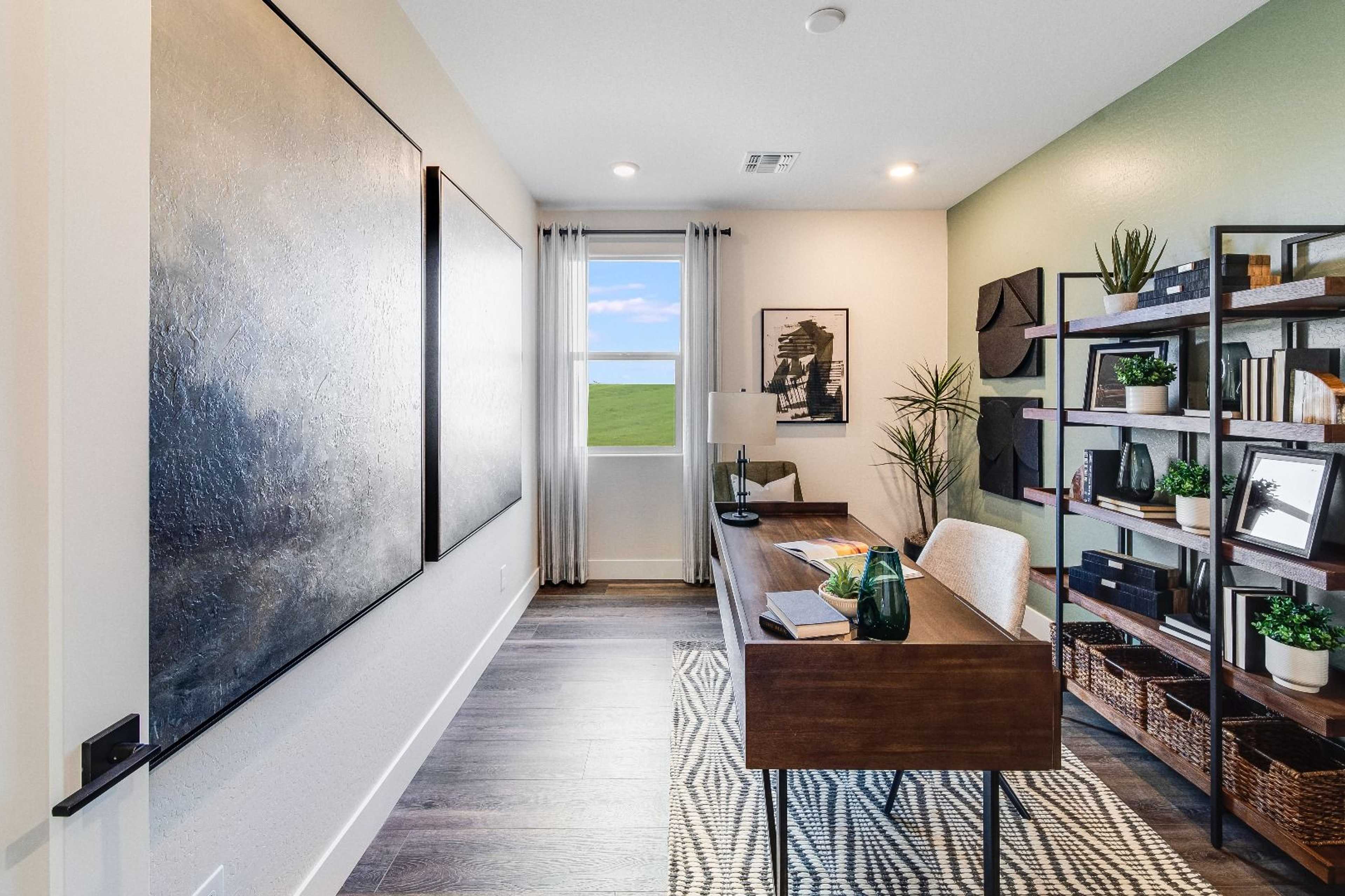 Spacious home office in South Ranch Western Collection, Prescott AZ featuring wooden desk, bookshelves, abstract art, and window view of fields