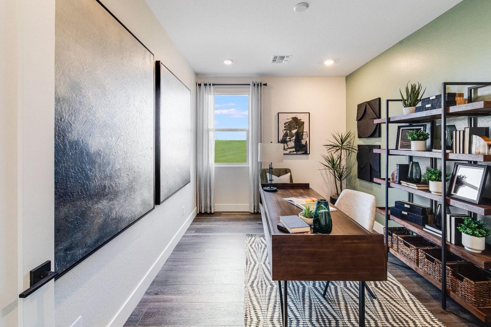 Spacious home office in South Ranch Western Collection, Prescott AZ featuring wooden desk, bookshelves, abstract art, and window view of fields