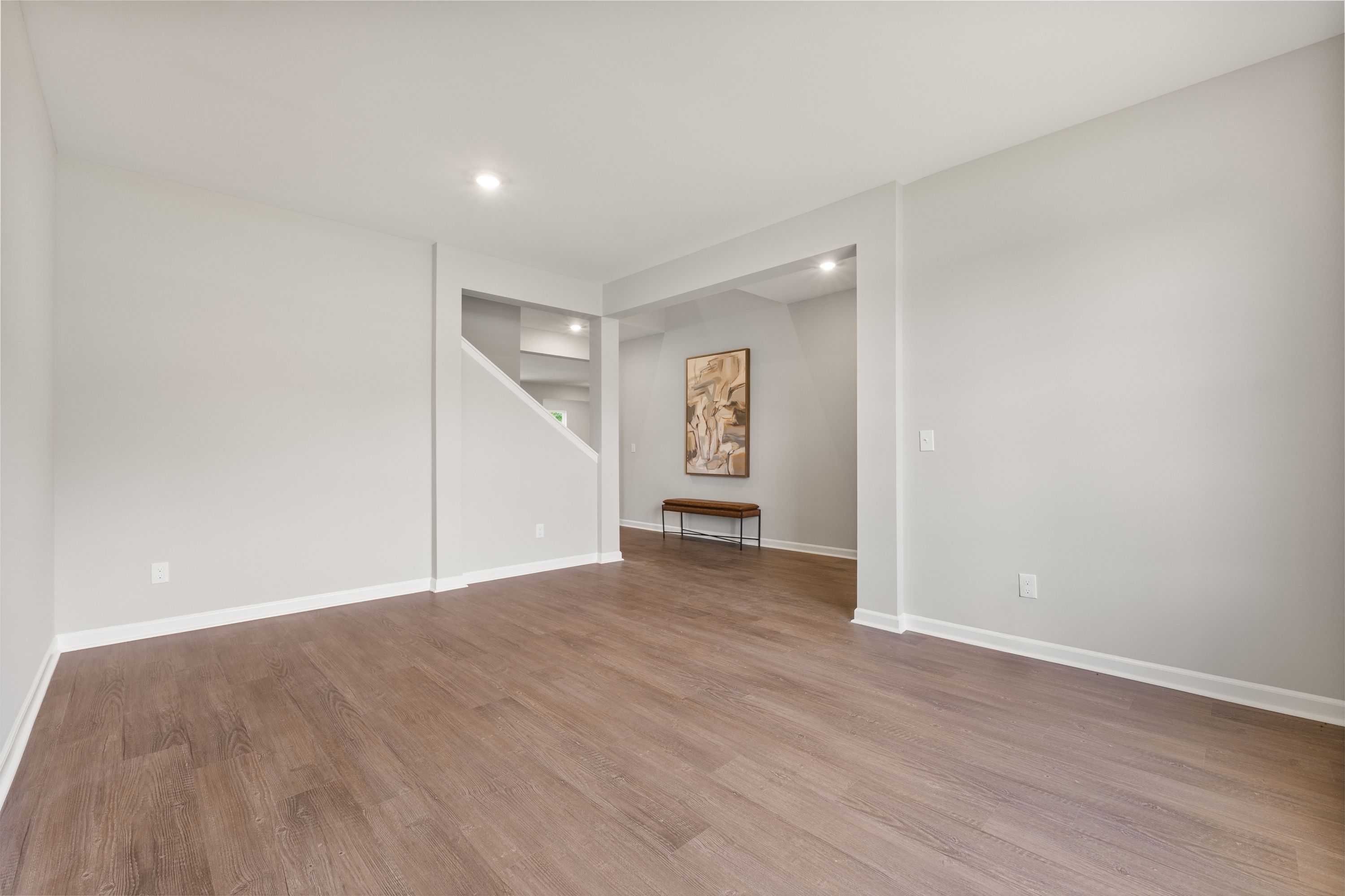 Spacious entryway in The Avalon E with hardwood floors, open staircase, and arched hallway by Evermore Homes