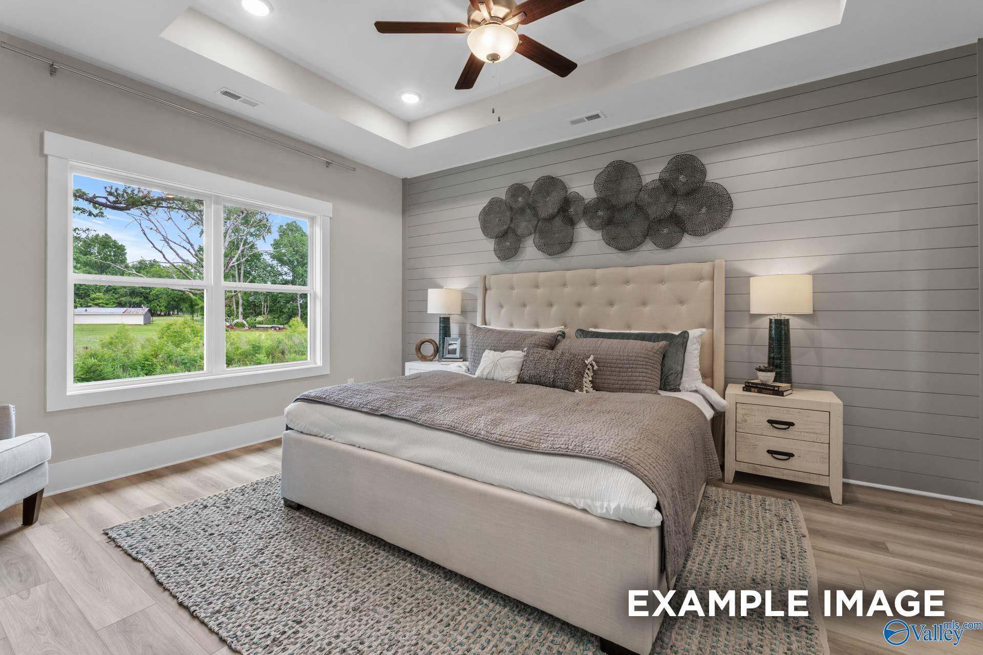 Elegant primary bedroom with tray ceiling, shiplap accent wall, and large window in Davidson Homes' The Everett B, Arab, Alabama