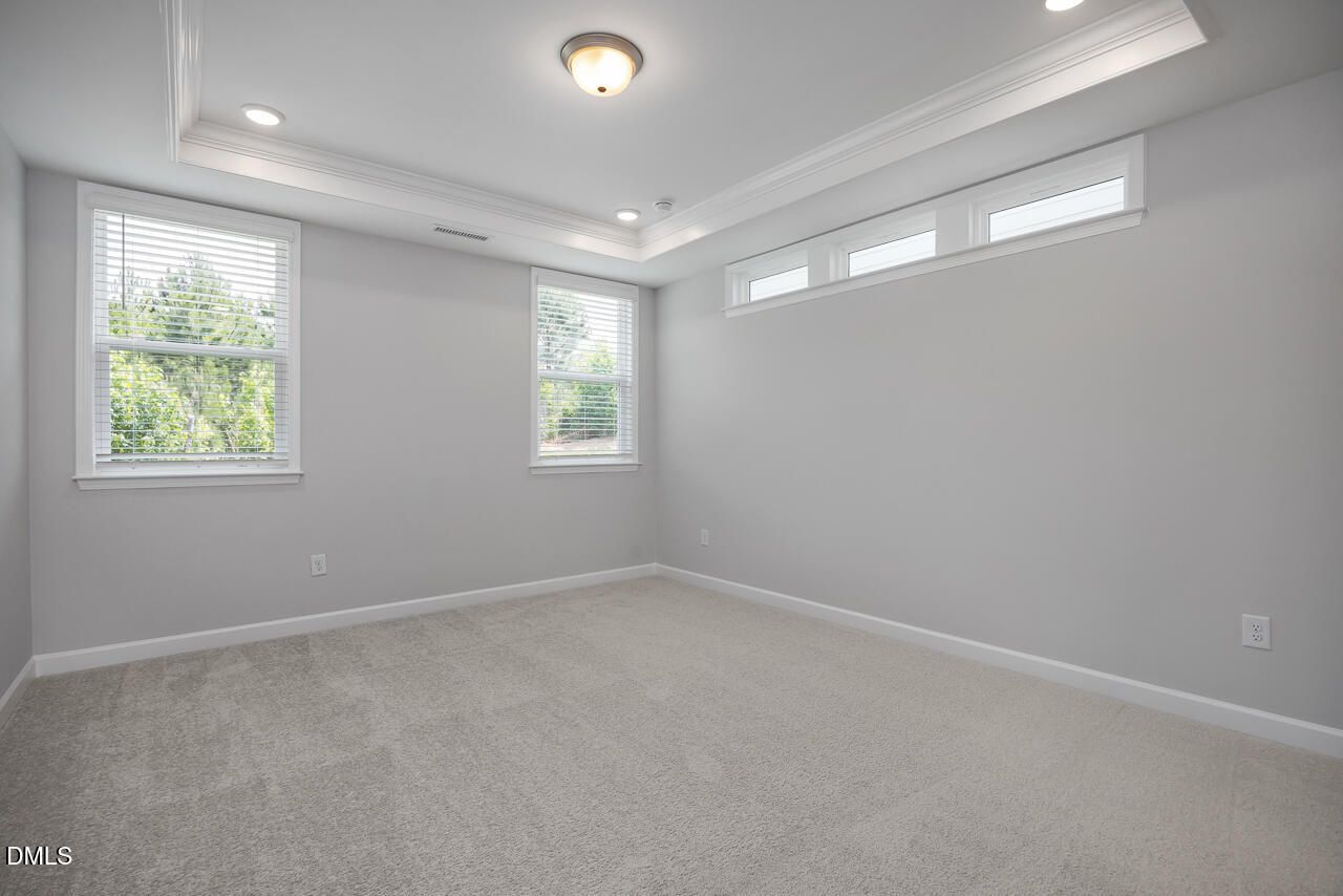 Bright bedroom with tray ceiling and transom windows in The Ashport L floor plan at Sage on North Main, Wake Forest, NC.