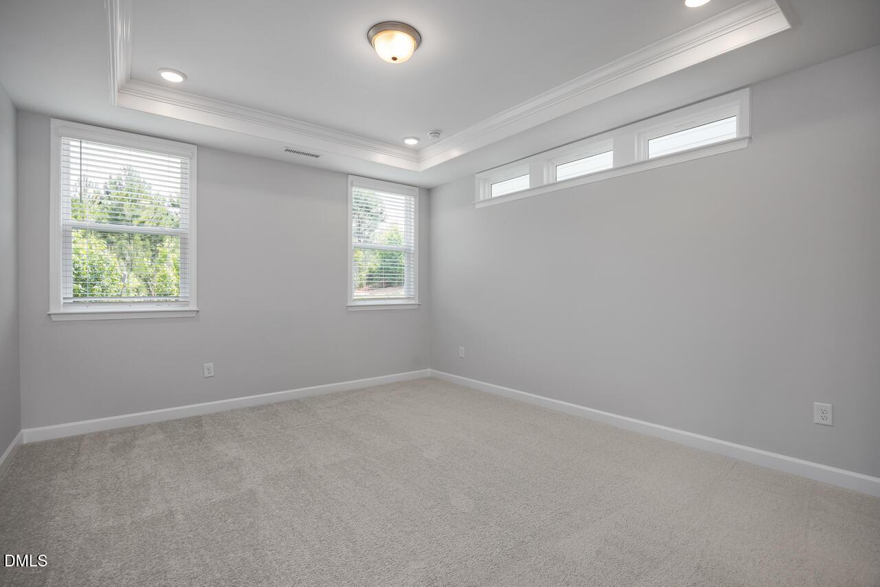 Bright bedroom with tray ceiling and transom windows in The Ashport L floor plan at Sage on North Main, Wake Forest, NC.