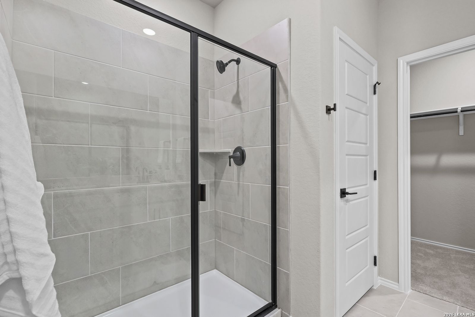 Modern walk-in shower with black fixtures and tile surround in The Daphne H floor plan at Hannah Heights, Seguin, Texas.