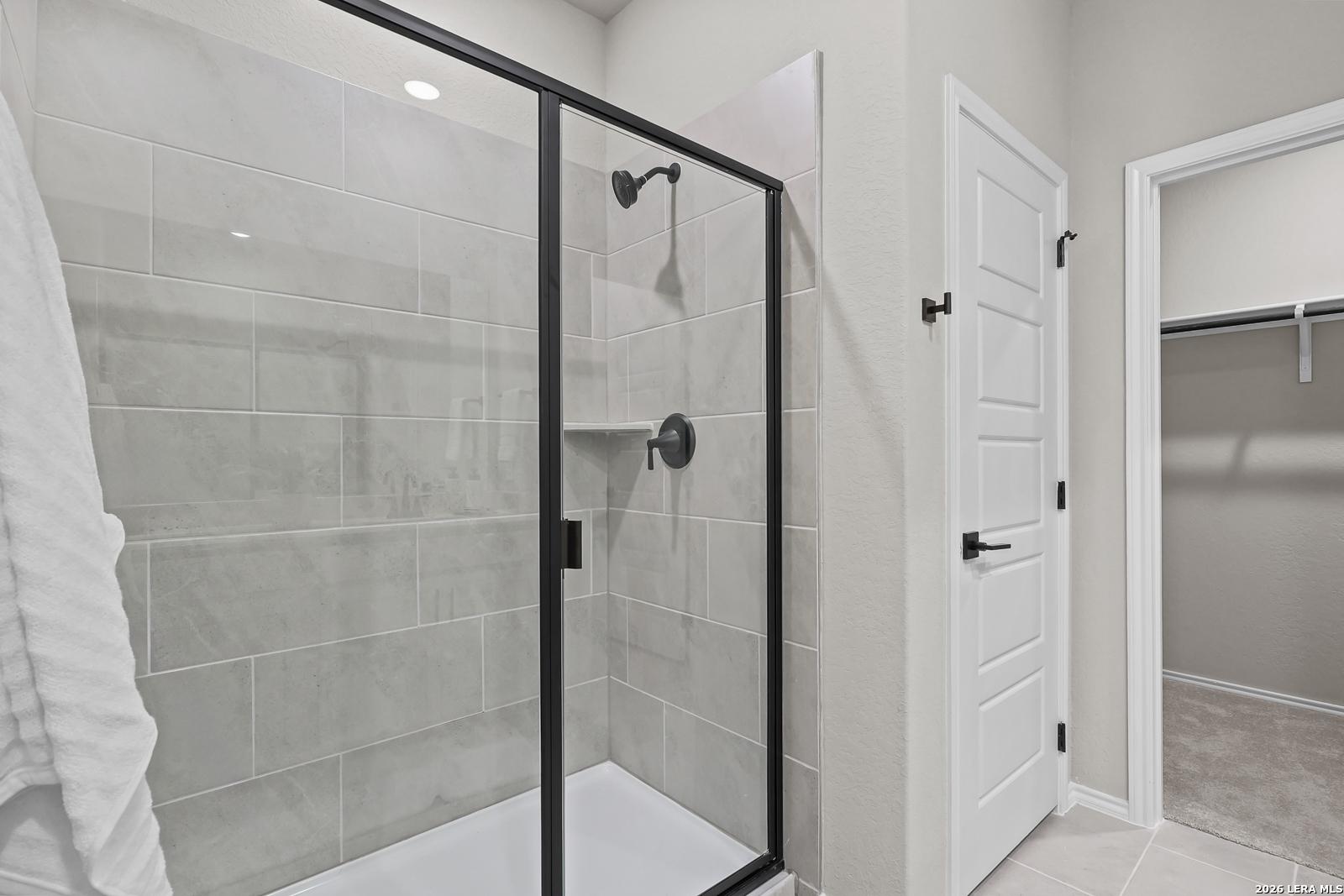 Modern walk-in shower with black fixtures and tile surround in The Daphne H floor plan at Hannah Heights, Seguin, Texas.