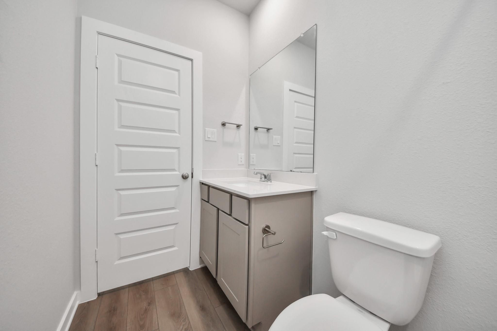 Modern half-bath with vanity, mirror, and toilet in The Riviera A floor plan by Davidson Homes in Emberly, Beasley, TX.