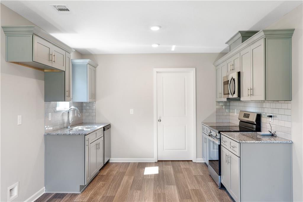 Modern kitchen with gray cabinets, granite countertops, and subway tile backsplash in The Washington plan, Phenix City.