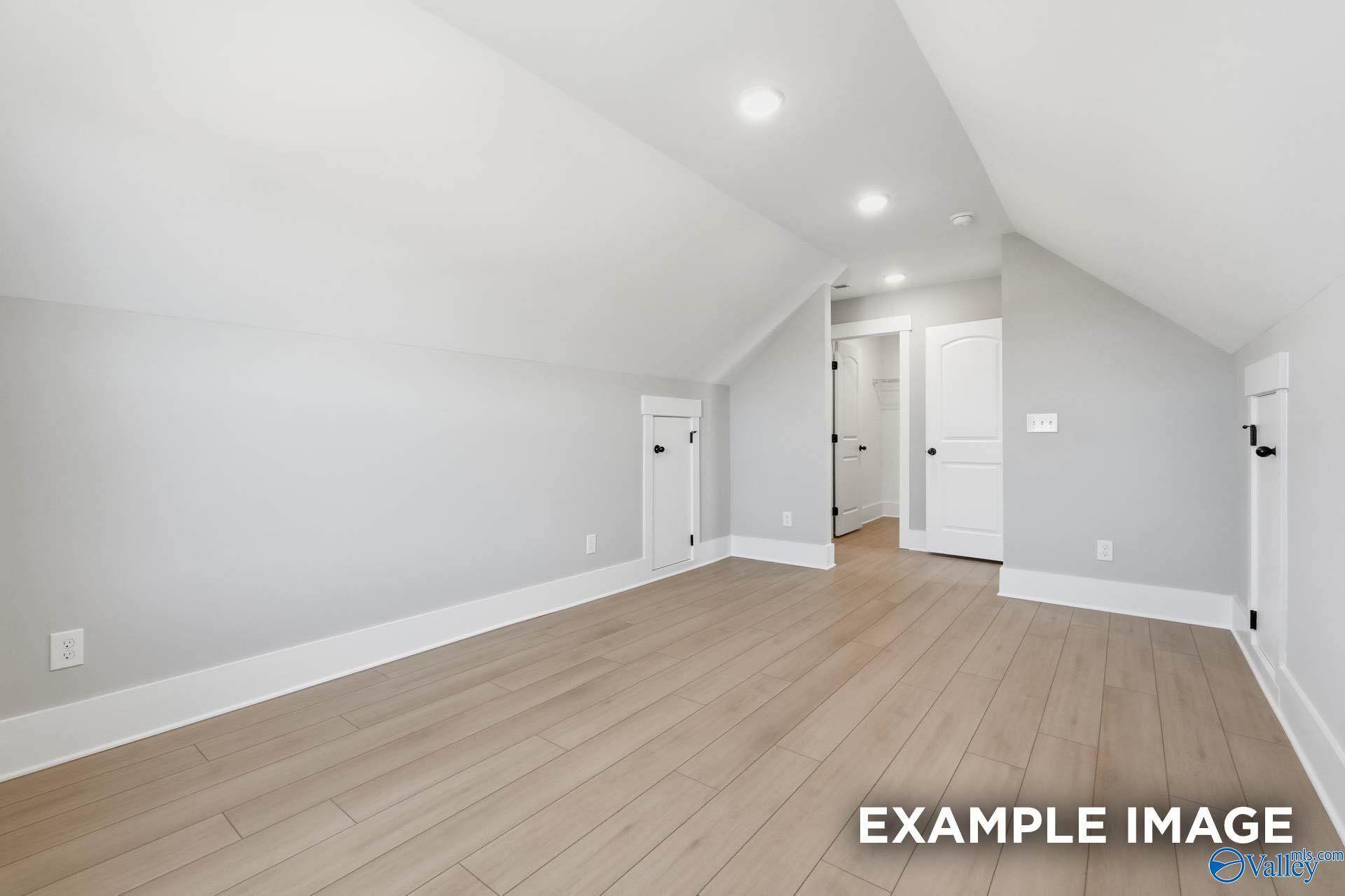 Spacious bonus room with vaulted ceiling, hardwood floors, and doorways in Davidson Homes The Emory, Decatur, Alabama