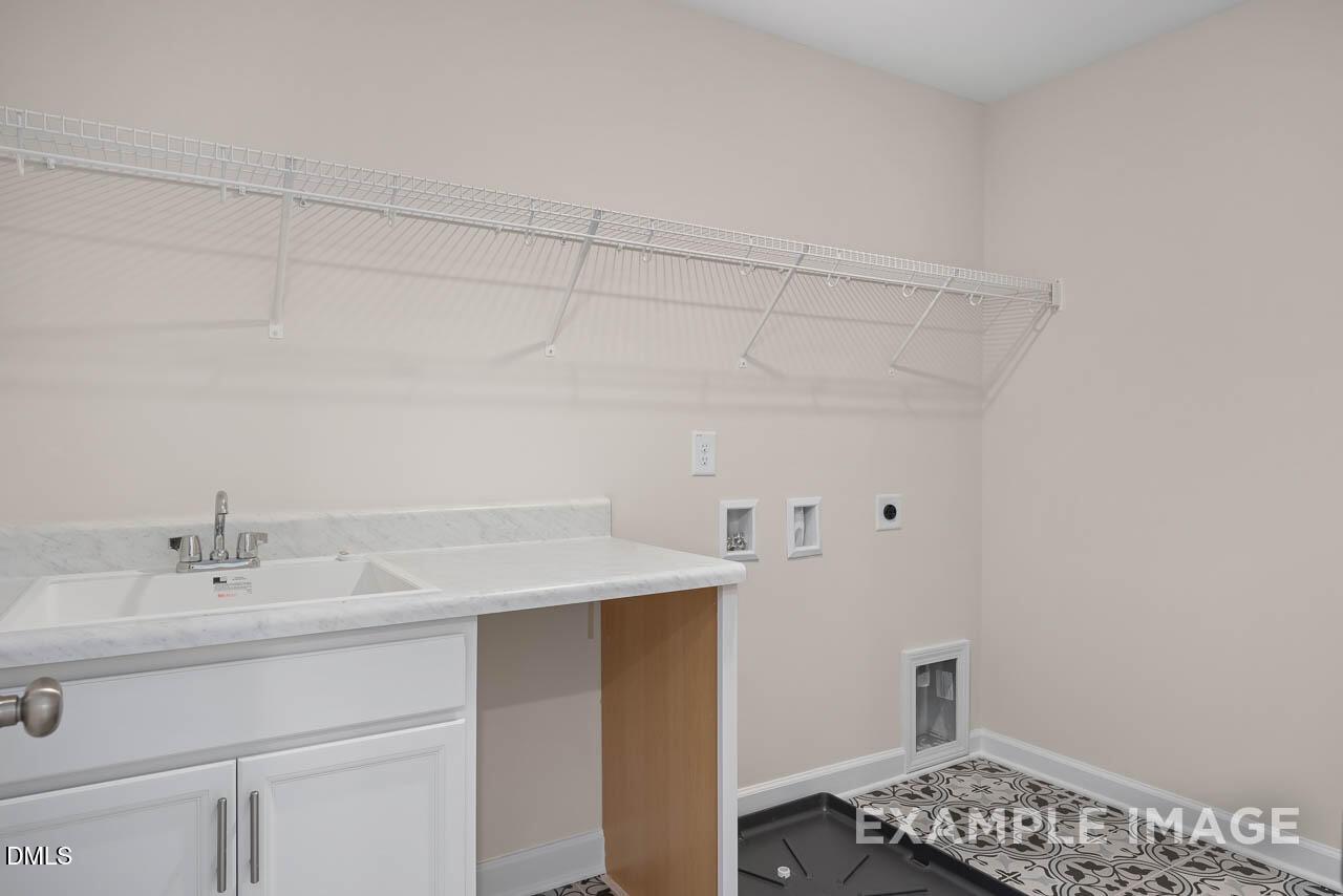 Modern laundry room with white utility sink, wire shelving, cabinets in The Willow D by Davidson Homes, Lillington, NC