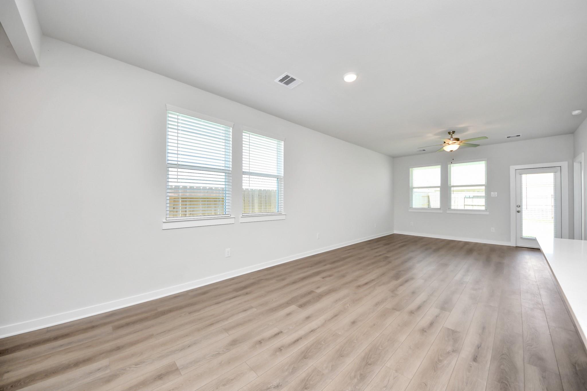 Bright open-concept living area with luxury vinyl plank flooring and ceiling fan in Davidson Homes The Costa A, Emberly, Beasley TX