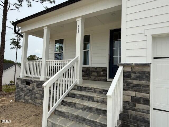 Covered front porch with stone foundation and white siding on The Birch II A home in Montrose, Aberdeen, North Carolina.