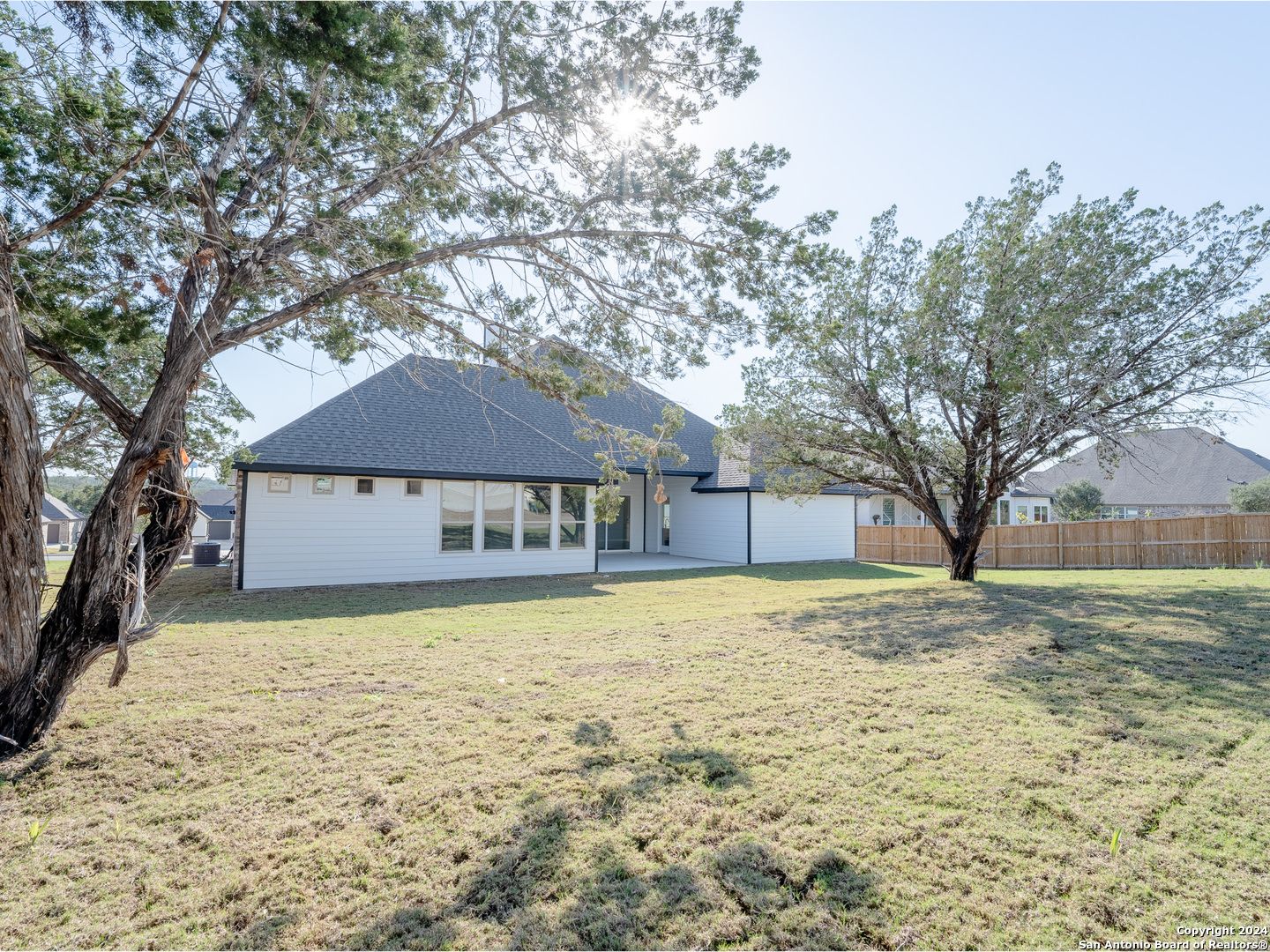 Covered patio with large windows overlooking lush green backyard and mature trees in Davidson Homes The Summerlin A, Castroville, Texas