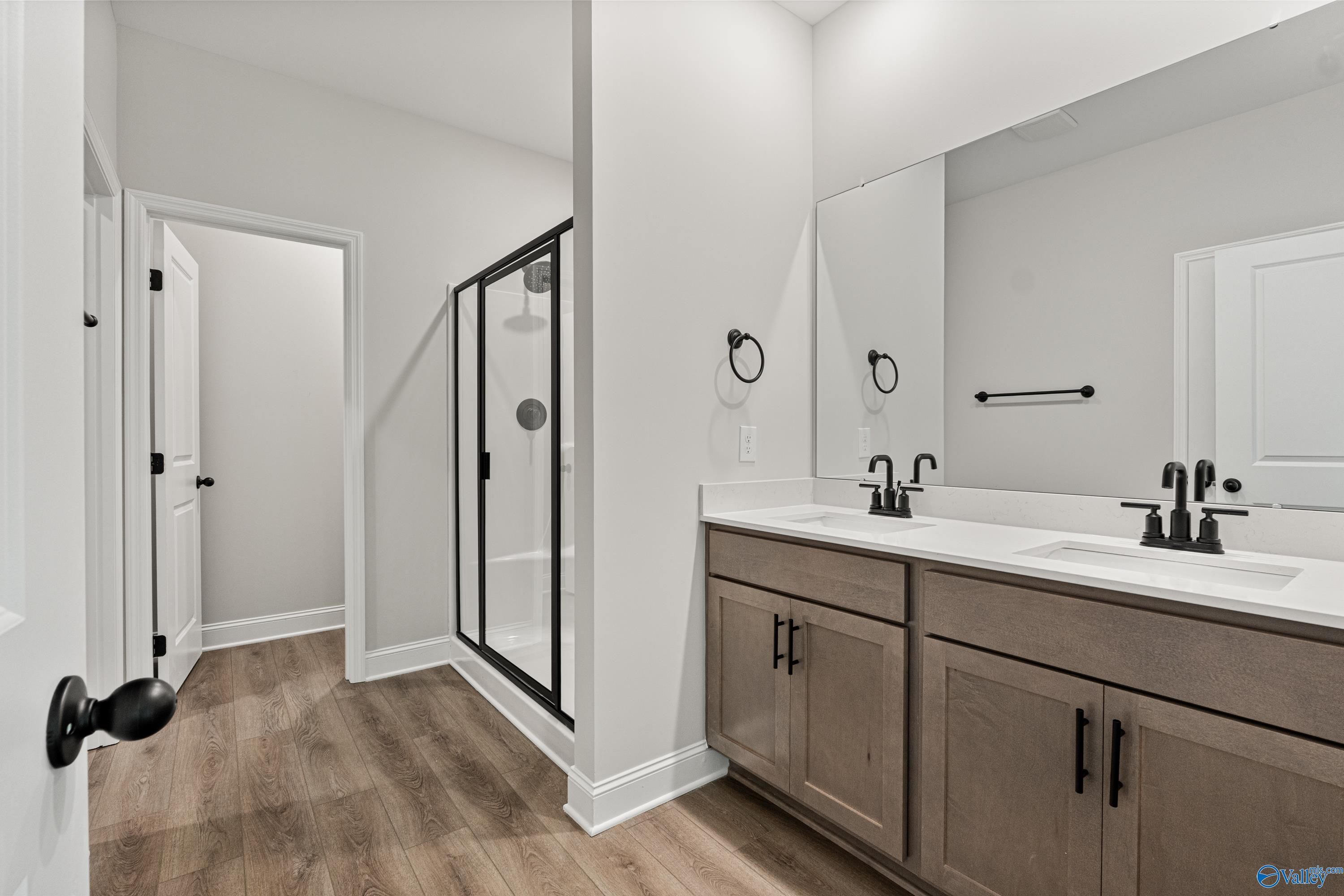 Modern master bath with double vanity, frameless glass shower, and laminate wood floors in The Daphne by Davidson Homes, Huntsville AL