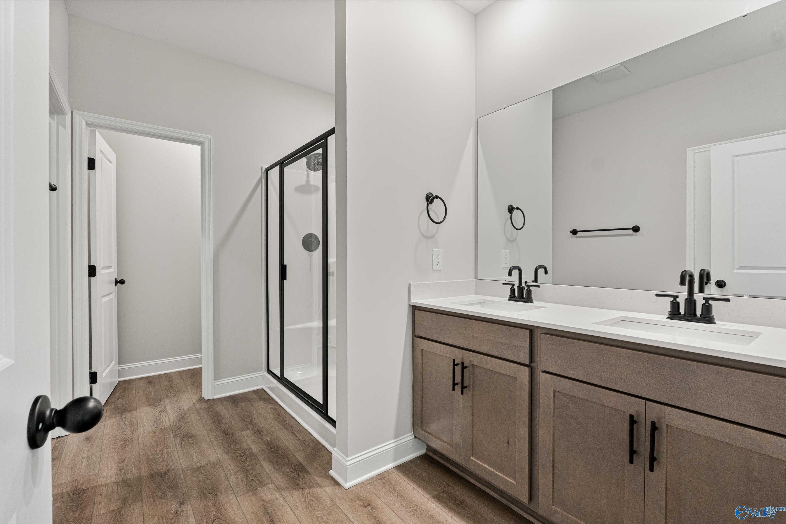Modern master bath with double vanity, frameless glass shower, and laminate wood floors in The Daphne by Davidson Homes, Huntsville AL