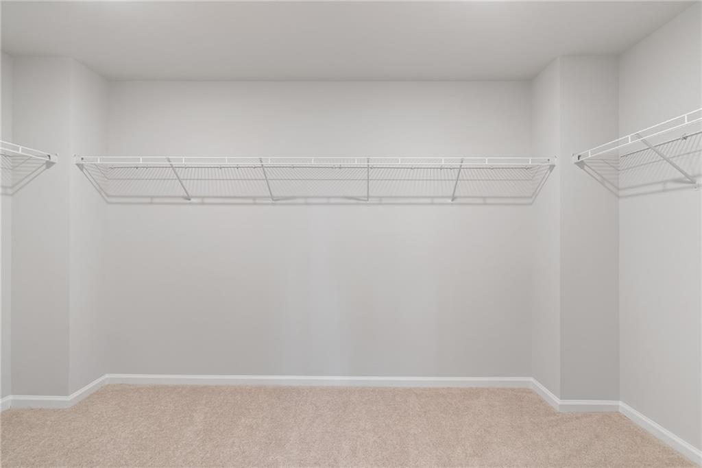 Spacious walk-in closet with white wire shelving on three walls in The Hickory A master suite, Davidson Homes, Winder, Georgia