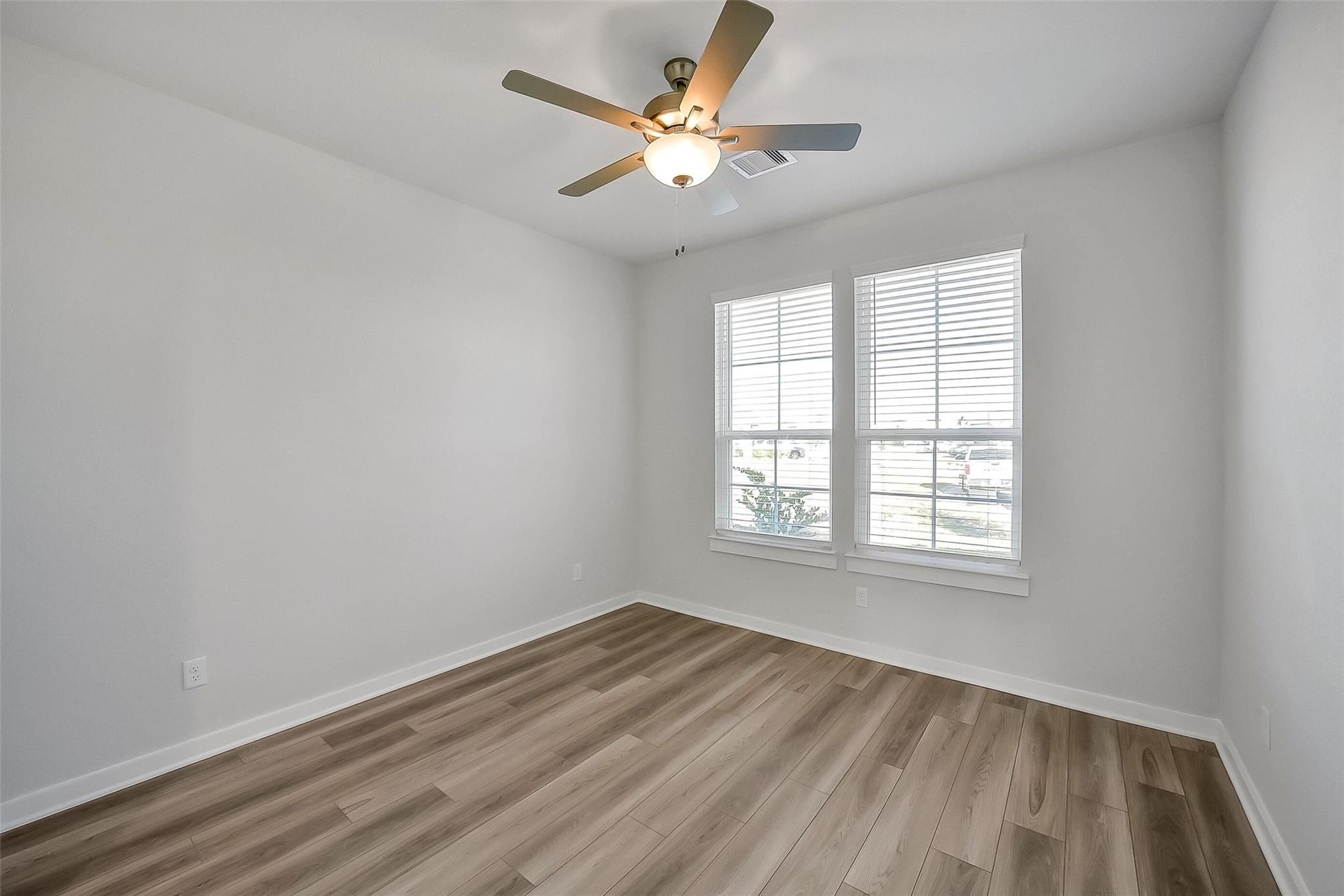 Bright secondary bedroom with ceiling fan, hardwood floors, and window blinds in Davidson Homes The Acadia A, Sunterra, Katy, Texas