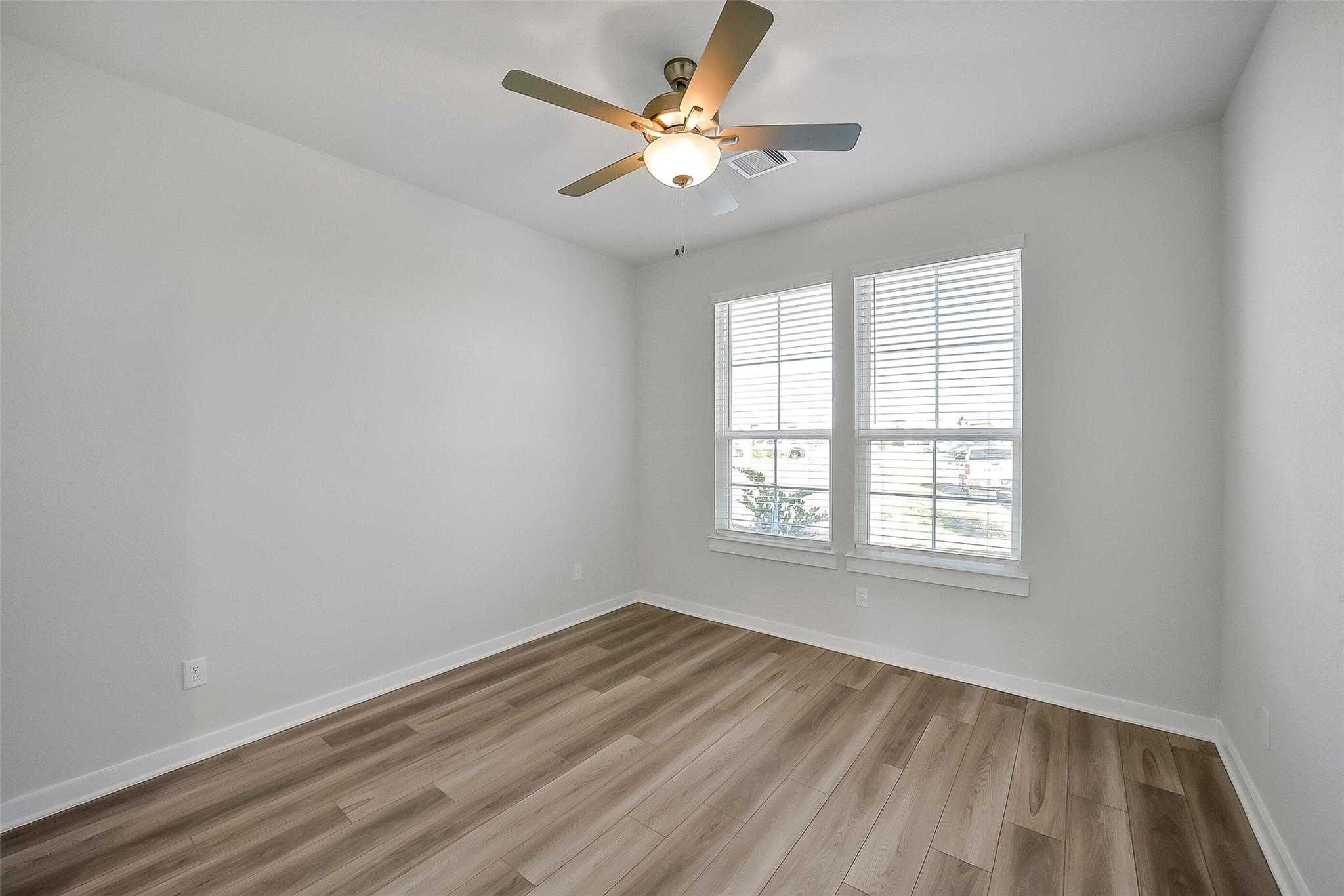 Bright secondary bedroom with ceiling fan, hardwood floors, and window blinds in Davidson Homes The Acadia A, Sunterra, Katy, Texas