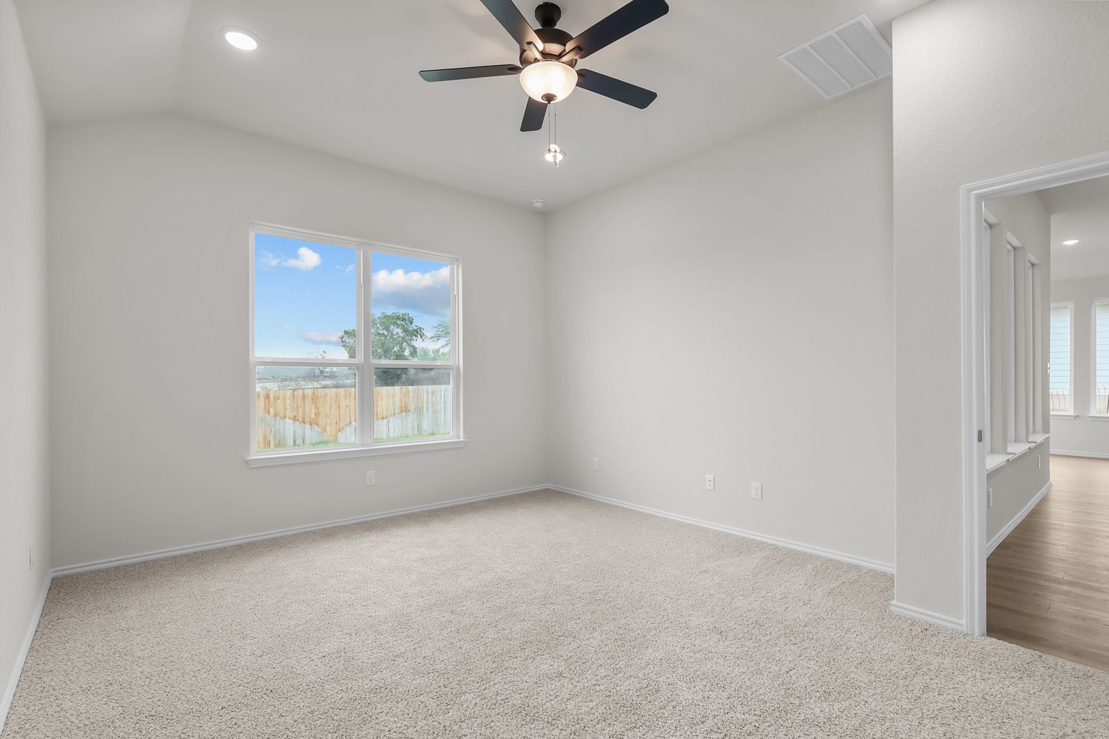Spacious master bedroom in The Sequoia C design featuring neutral carpeting, vaulted ceilings, and a ceiling fan.