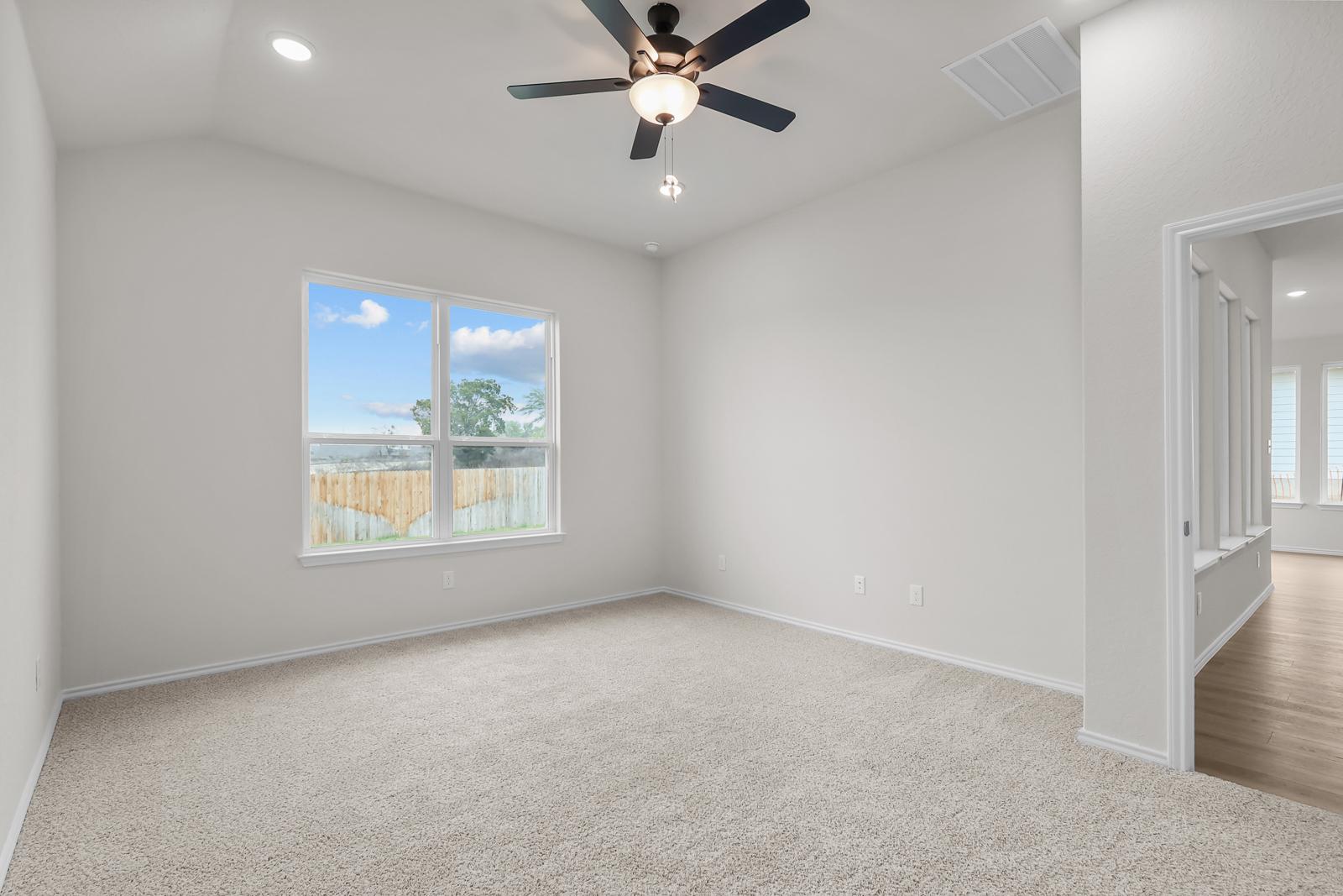 Spacious master bedroom in The Sequoia C design featuring neutral carpeting, vaulted ceilings, and a ceiling fan.