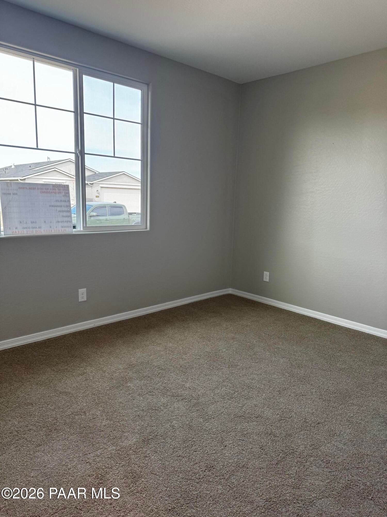 Bright empty bedroom with gray walls, large window overlooking exterior, and beige carpet in Davidson Homes Durango II B, Prescott, AZ
