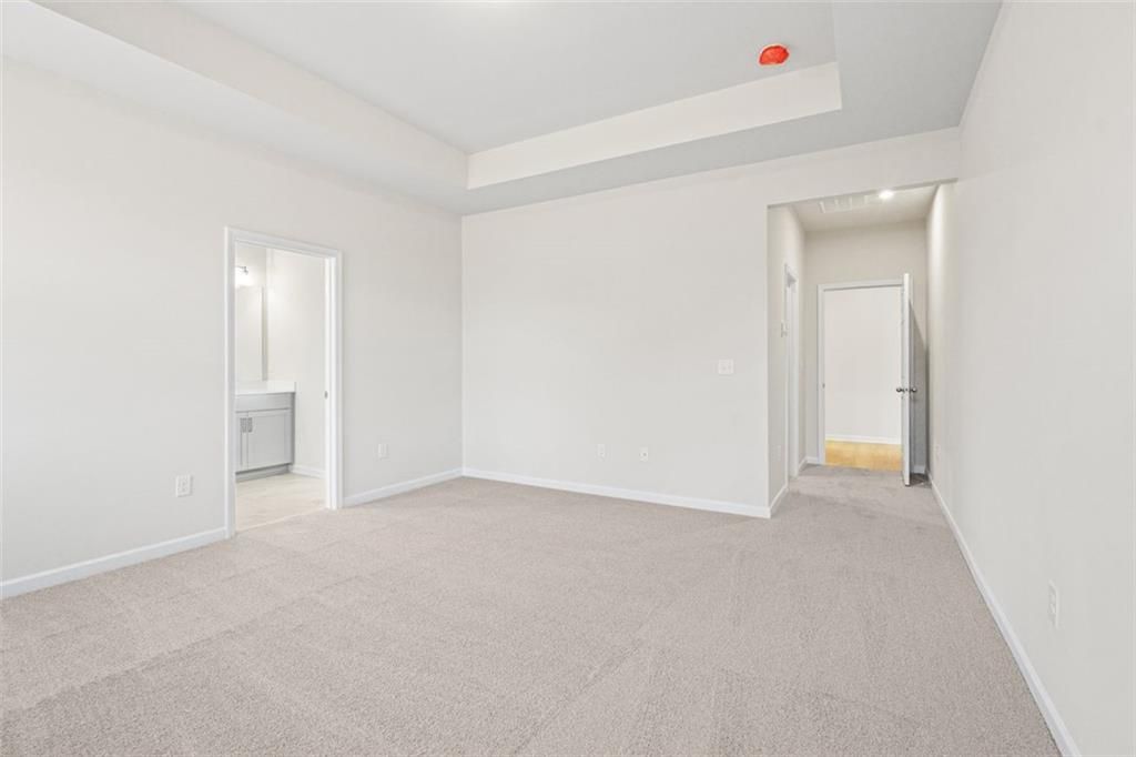 Spacious master bedroom with tray ceiling, en-suite bath, and walk-in closet in Davidson Homes The Glenwood C at Wehunt Meadows, Hoschton