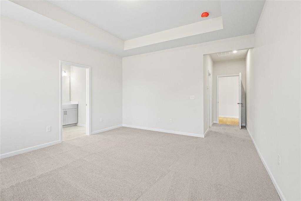 Spacious master bedroom with tray ceiling, en-suite bath, and walk-in closet in Davidson Homes The Glenwood C at Wehunt Meadows, Hoschton