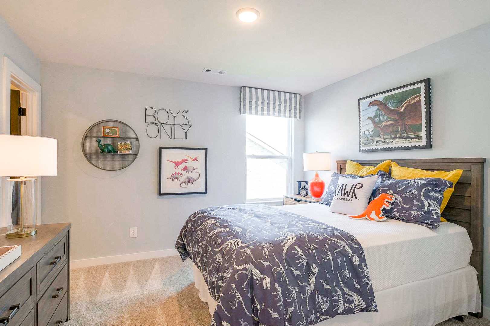 Dinosaur-themed boy's bedroom at The Meadows in Smyrna TN with gray bedding, toy shelves and posters