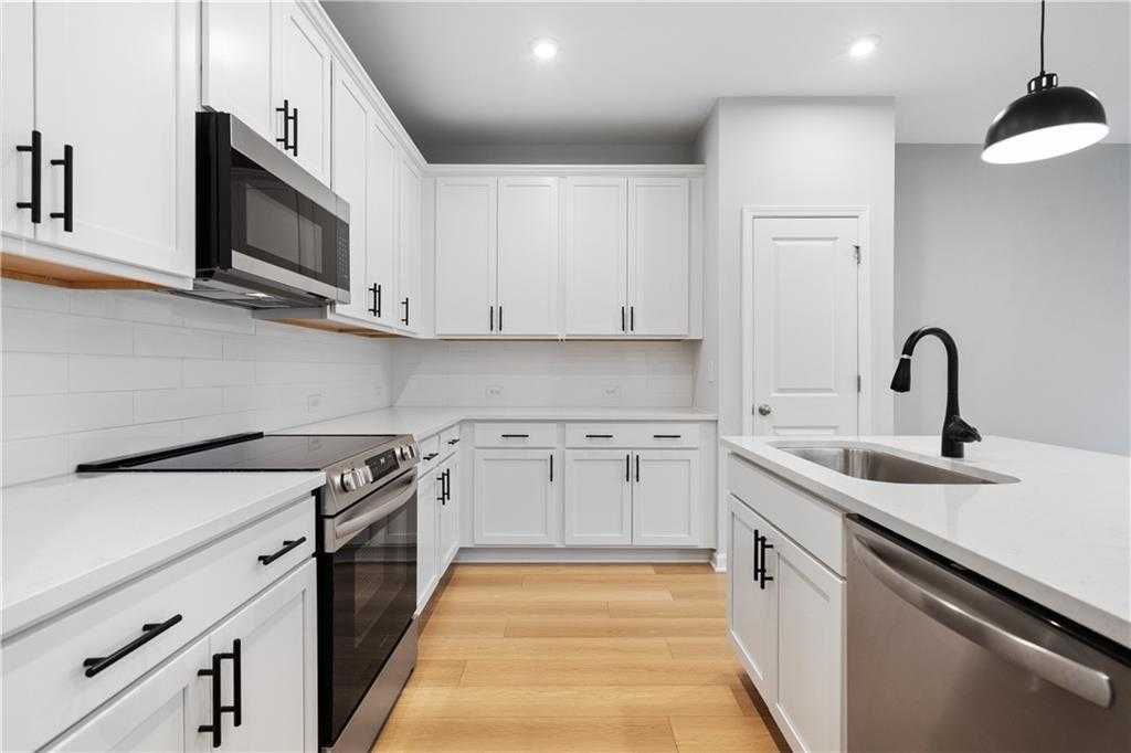 Modern white kitchen with stainless appliances, quartz island, and subway tile backsplash in Davidson Homes The Durant A, Emerson, GA