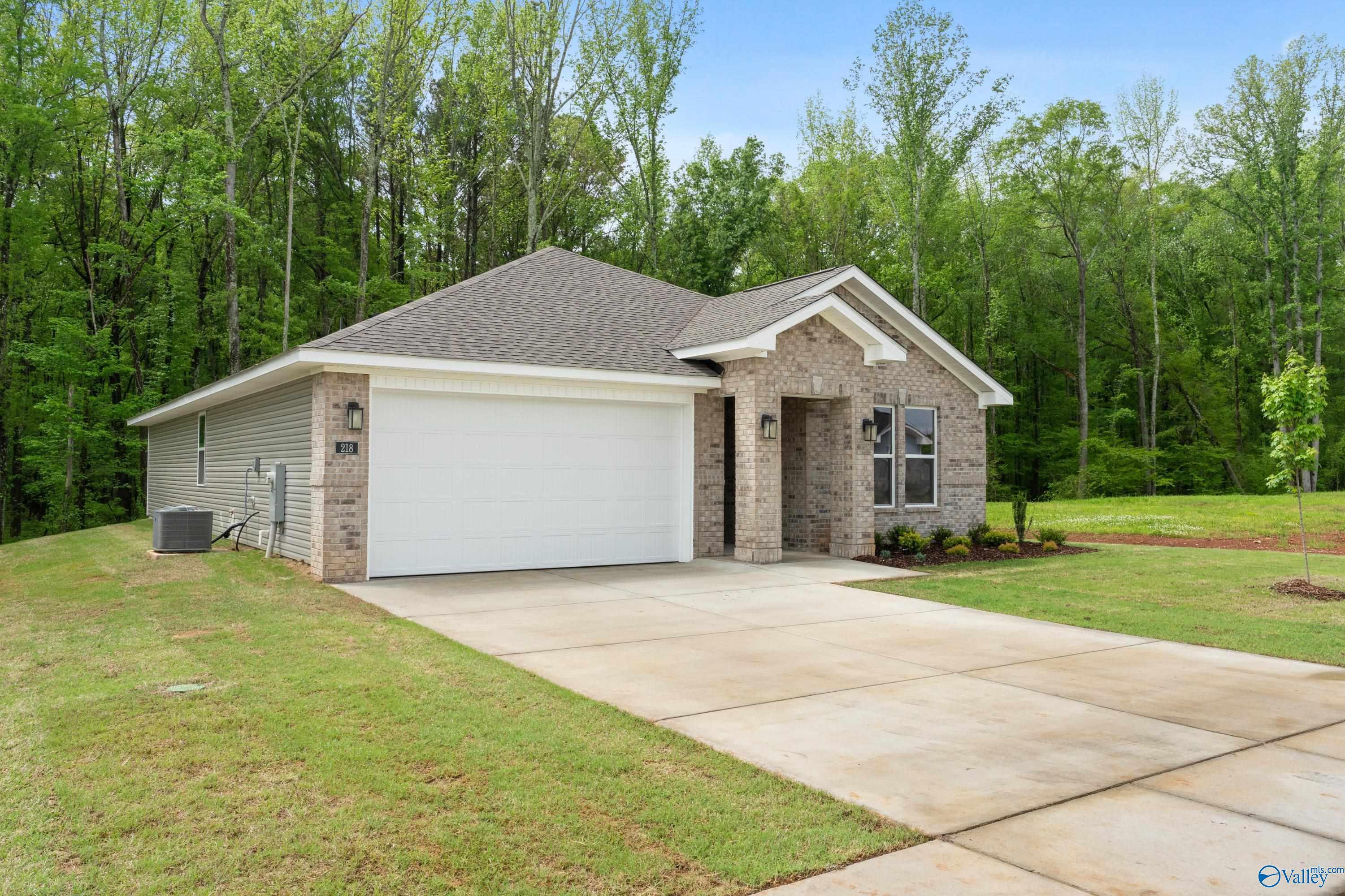 Davidson Homes The Luna: 1-story brick home with 2-car garage, driveway, and wooded yard in Forest Glen, Hazel Green, Alabama