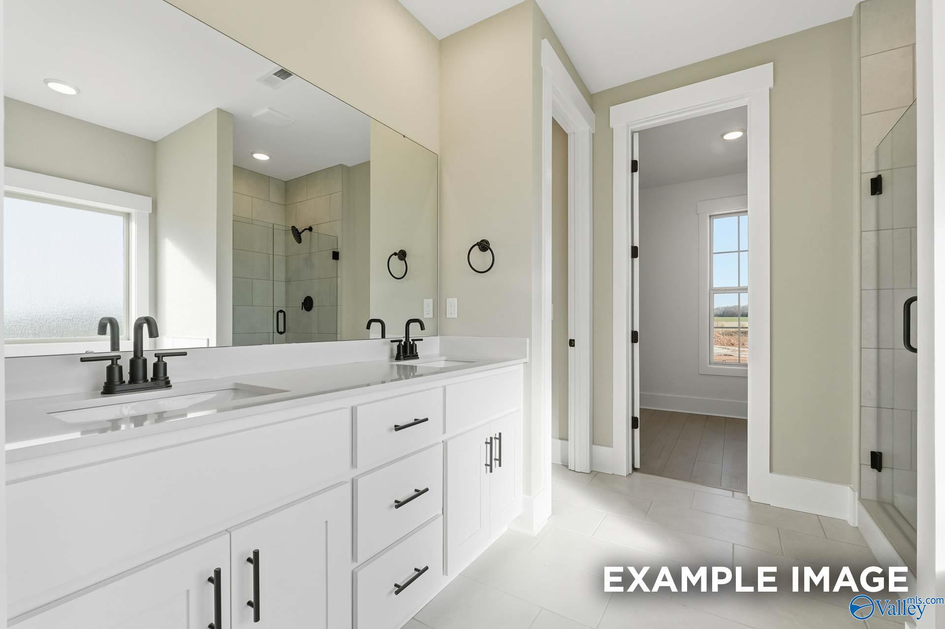 Modern master bathroom with double white vanity, large mirrors, frameless shower, and window in Davidson Homes The Emory, Decatur, AL