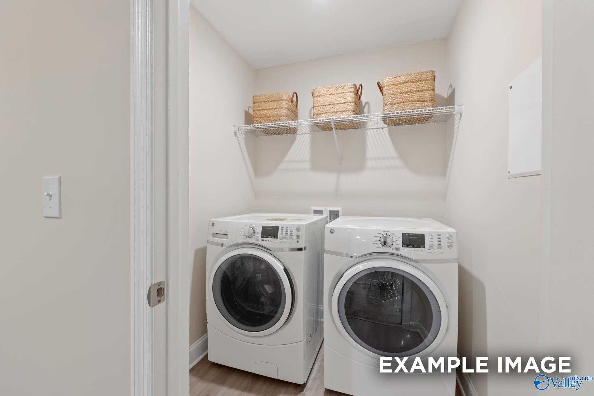 Modern laundry room featuring side-by-side white washer and dryer, wicker basket shelves in Davidson Homes The Camden B, Pavilion, Huntsville, Alabama