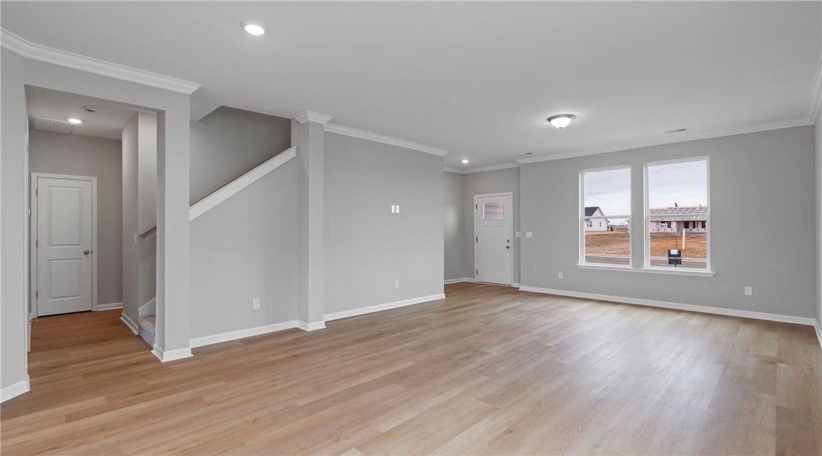 Spacious foyer with hardwood floors, gray walls, staircase, and large windows in Evermore Homes The Stella D, Cusseta, Alabama