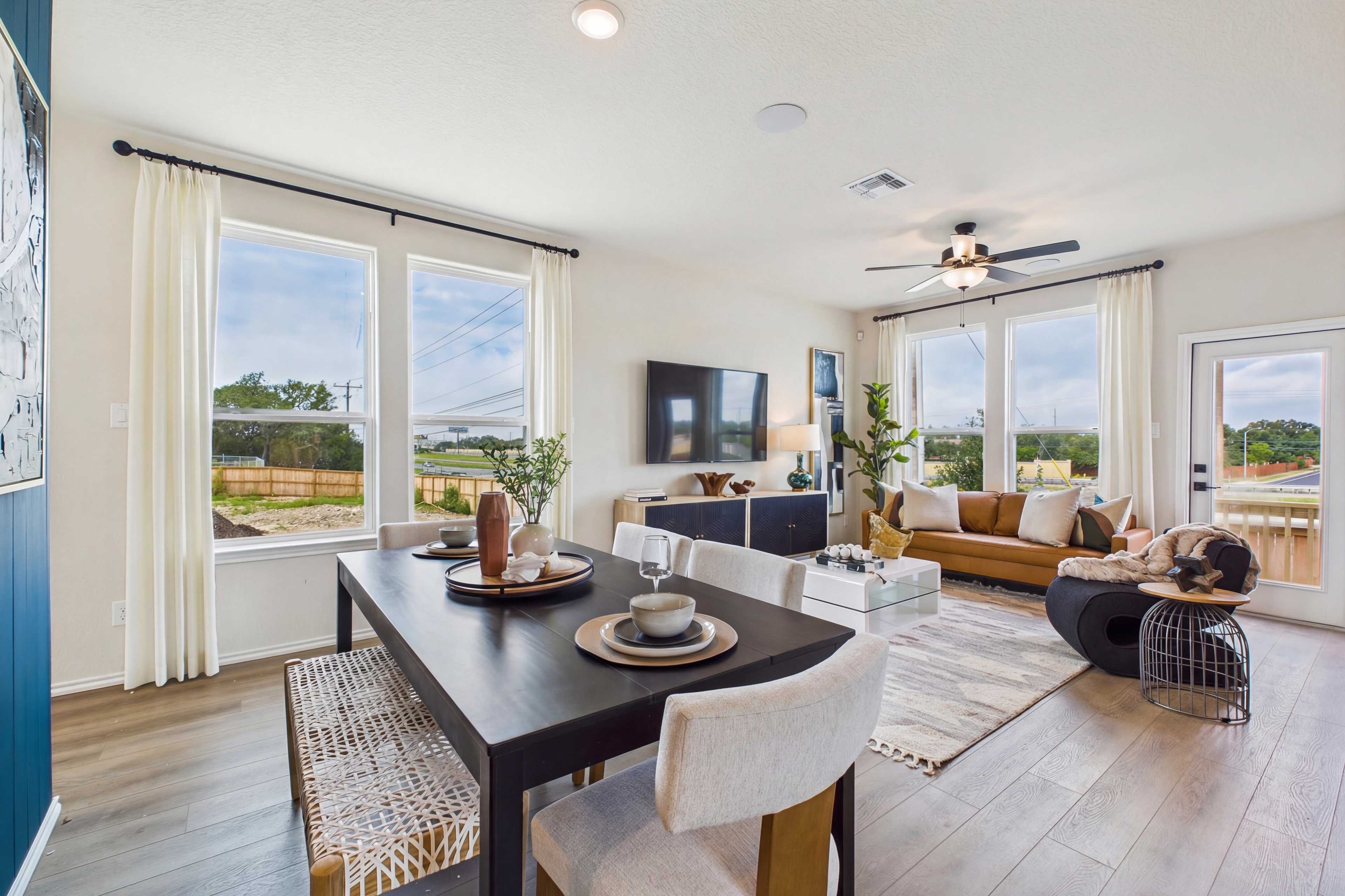 Open-concept living dining room at Meadows at Oak Creek San Antonio TX with hardwood floors large windows modern sofa and dining table