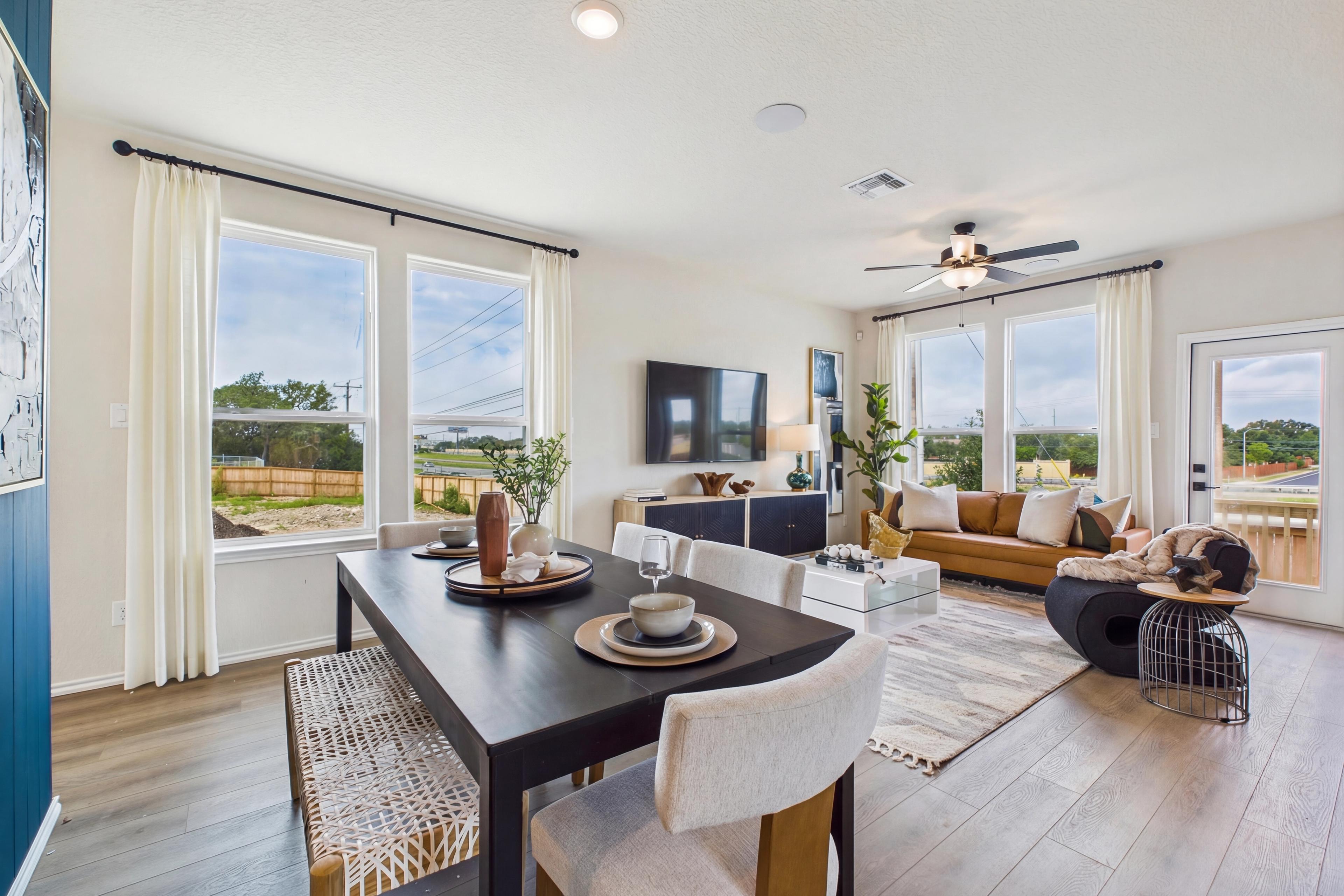 Open-concept living dining room at Meadows at Oak Creek San Antonio TX with hardwood floors large windows modern sofa and dining table