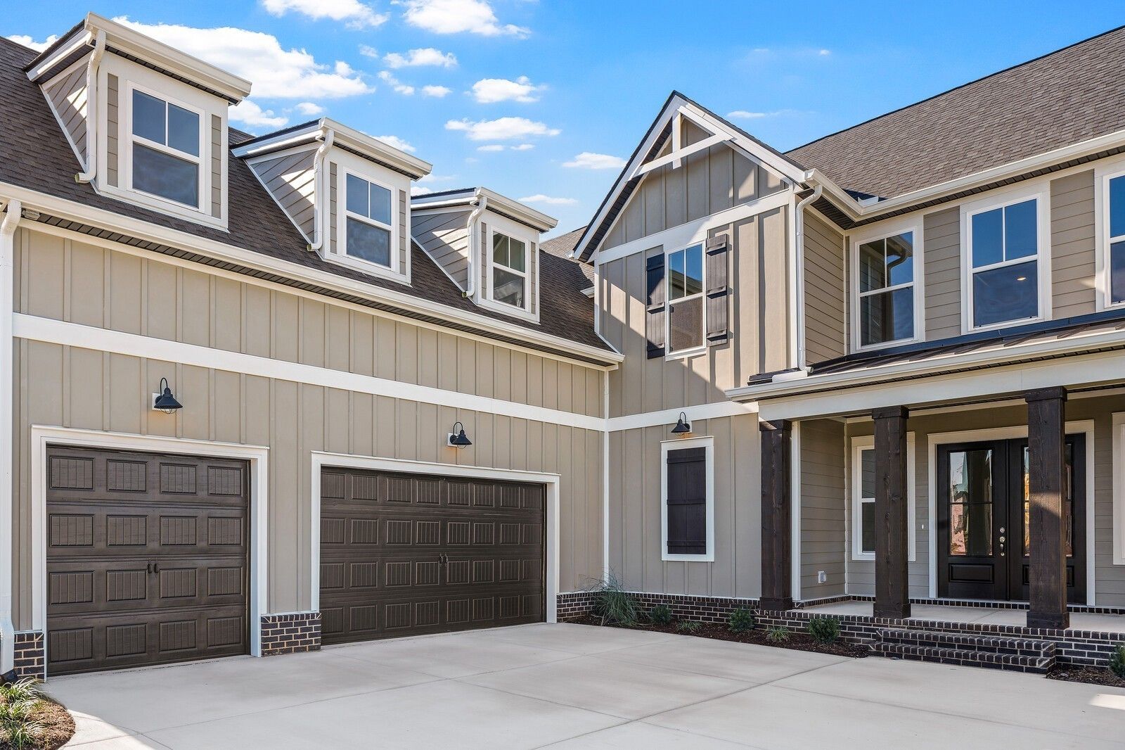 Two-story beige home with three-car garage, dormer windows, columned porch in Shelton Square, Murfreesboro, Tennessee
