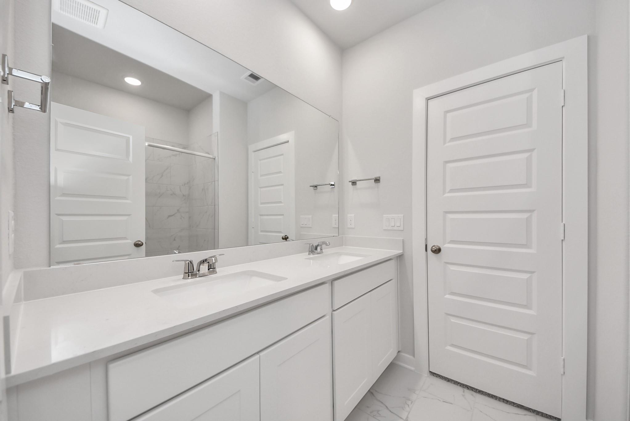 Modern primary bathroom with double vanity and walk-in shower in The Sabine E floor plan at Windmill Estates, Magnolia.