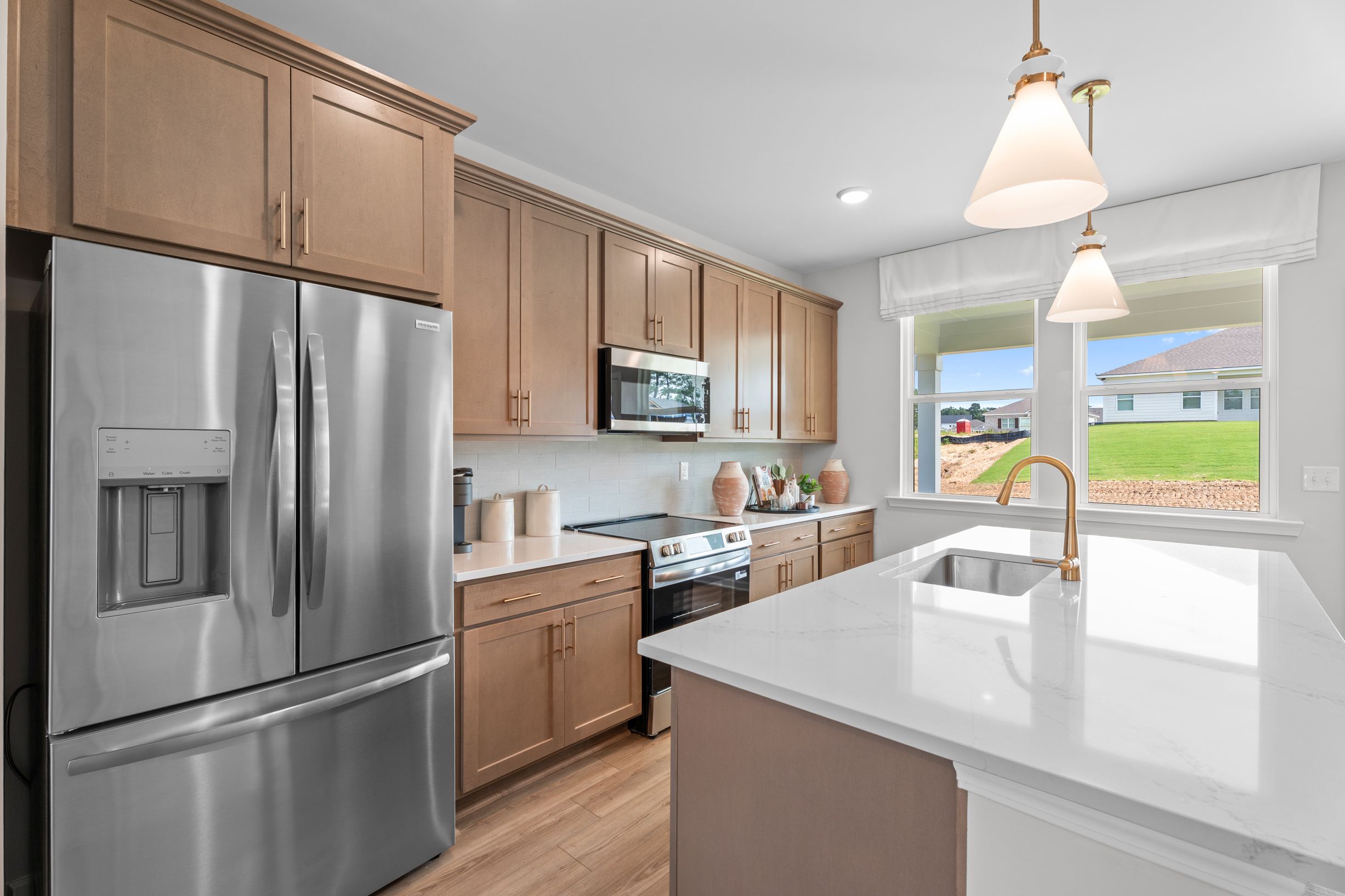 Modern kitchen at Links Crossing in Auburn, Alabama by Davidson Homes with quartz island, wood cabinets, and appliances.