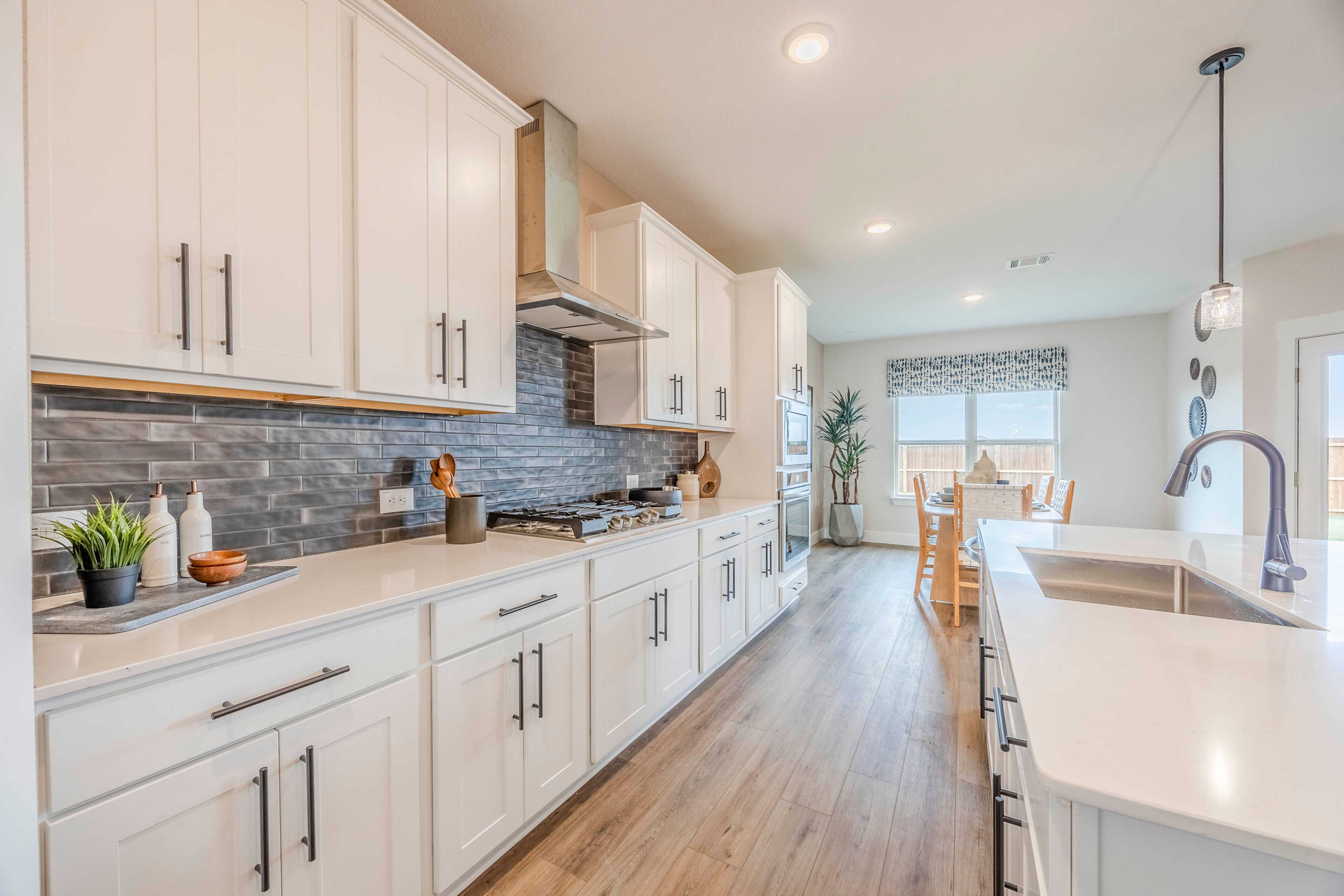 Spacious Rockford kitchen by Davidson Homes with white shaker cabinets, quartz island, gas range, and open dining nook