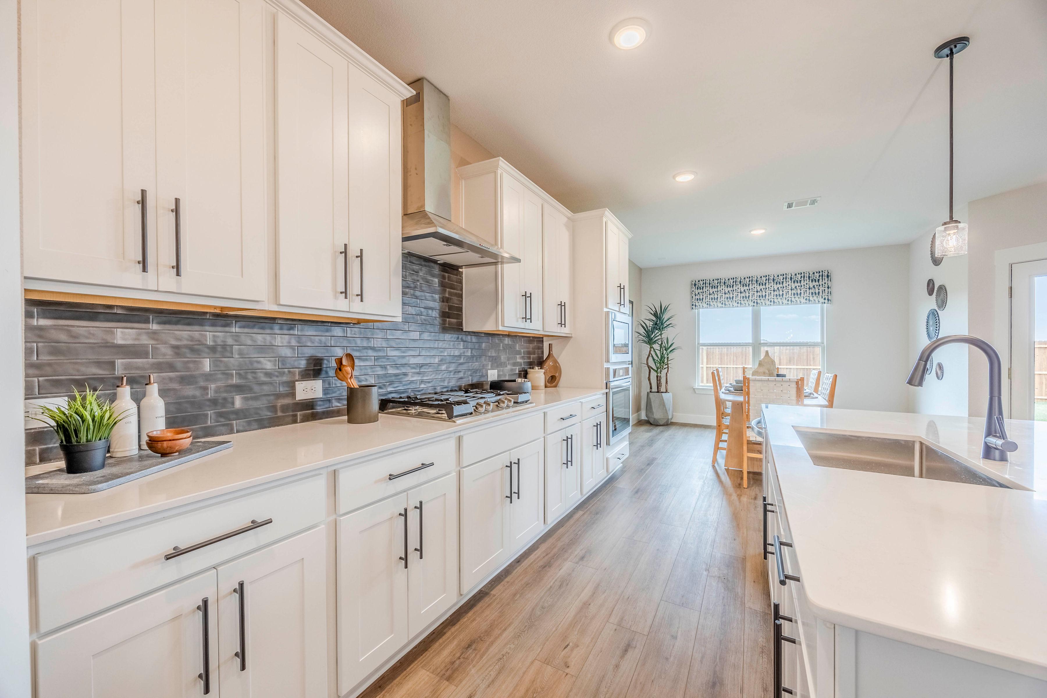 Open-concept kitchen at Waverly Estates in Josephine TX with white shaker cabinets, quartz counters, subway tile backsplash, hardwood floors, and dining area